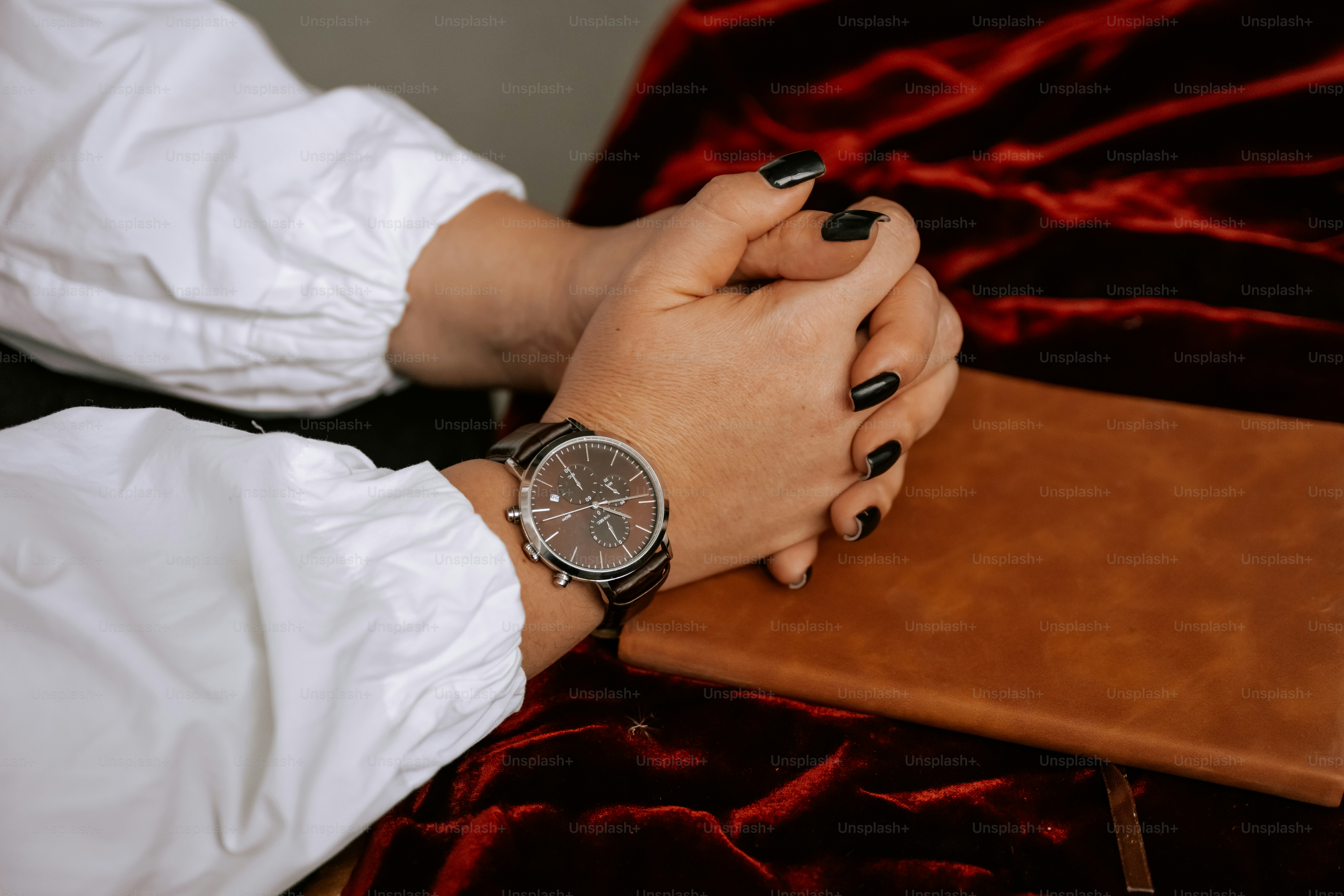 A woman's hands resting on a red velvet covered table