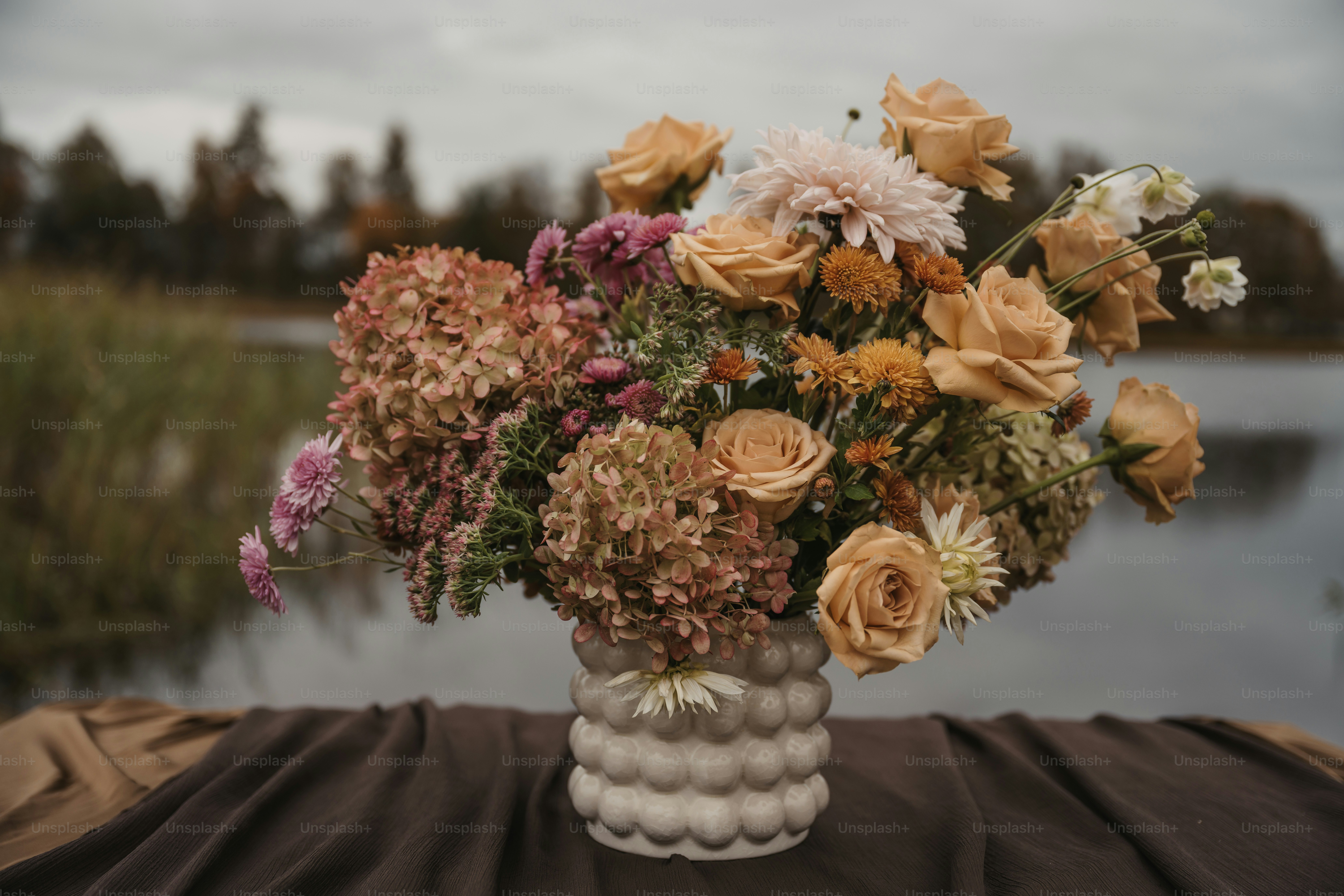 Un vase rempli de nombreuses fleurs posé sur une table