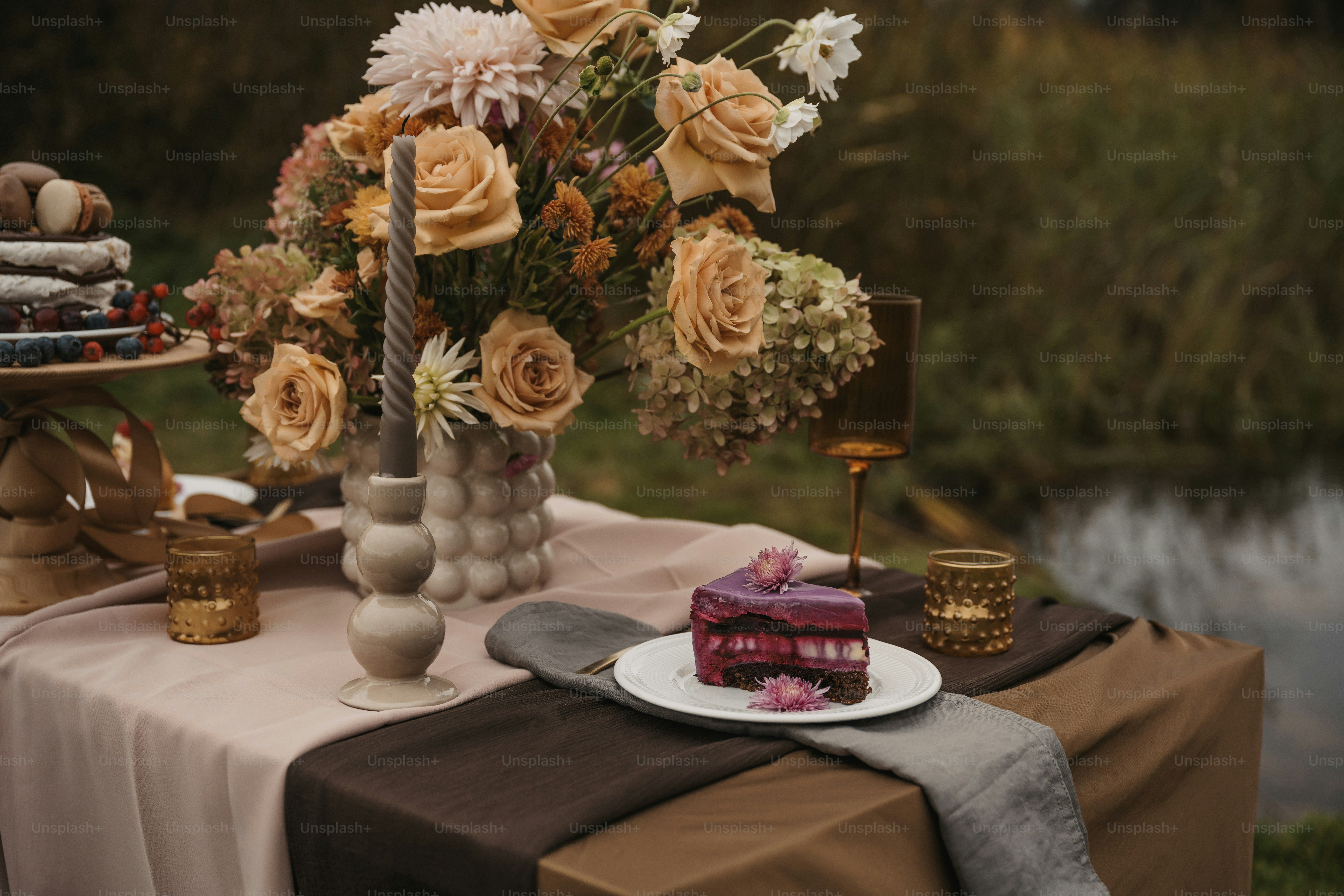 Une table surmontée d’un gâteau et d’un vase rempli de fleurs