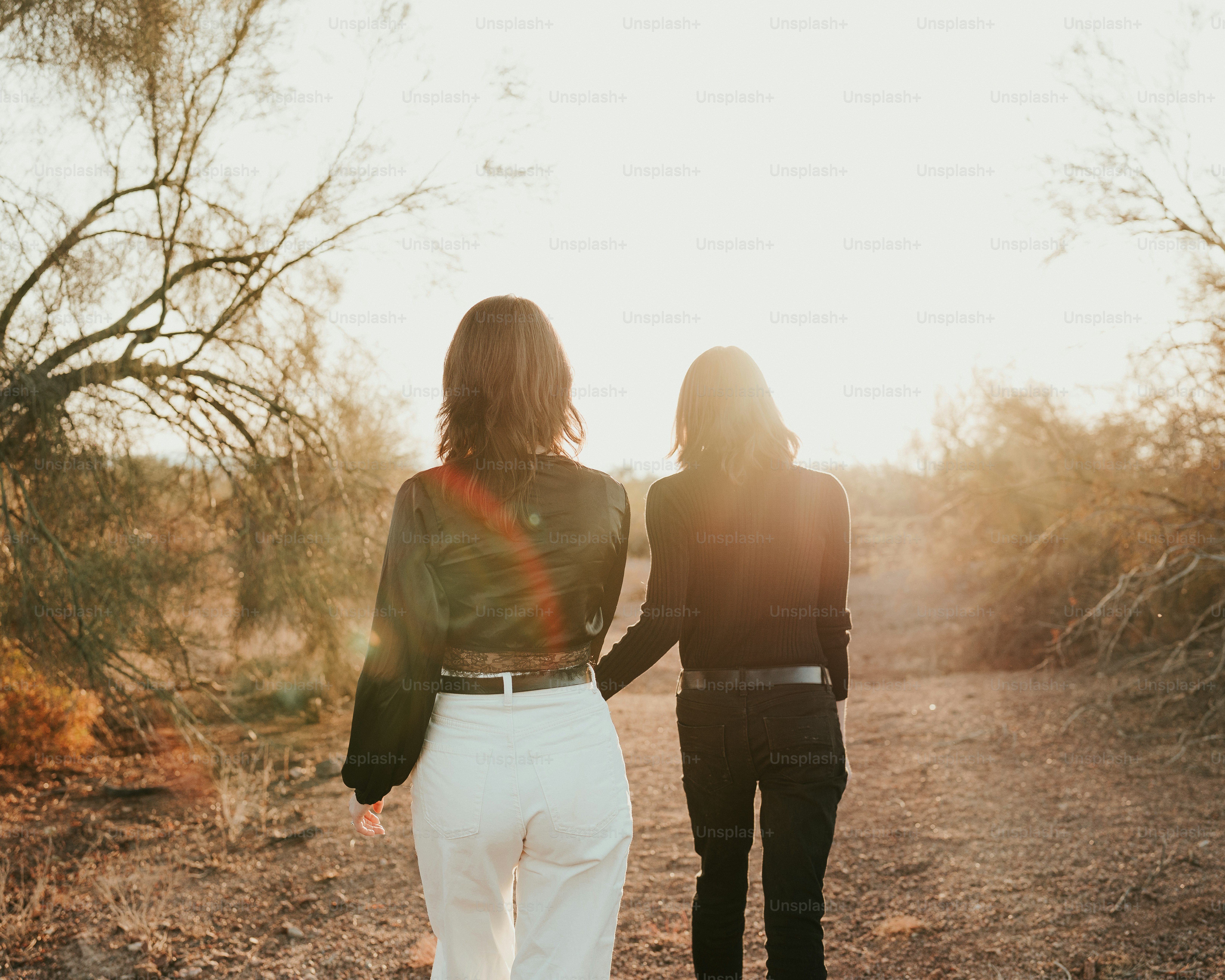 A couple of women walking down a dirt road