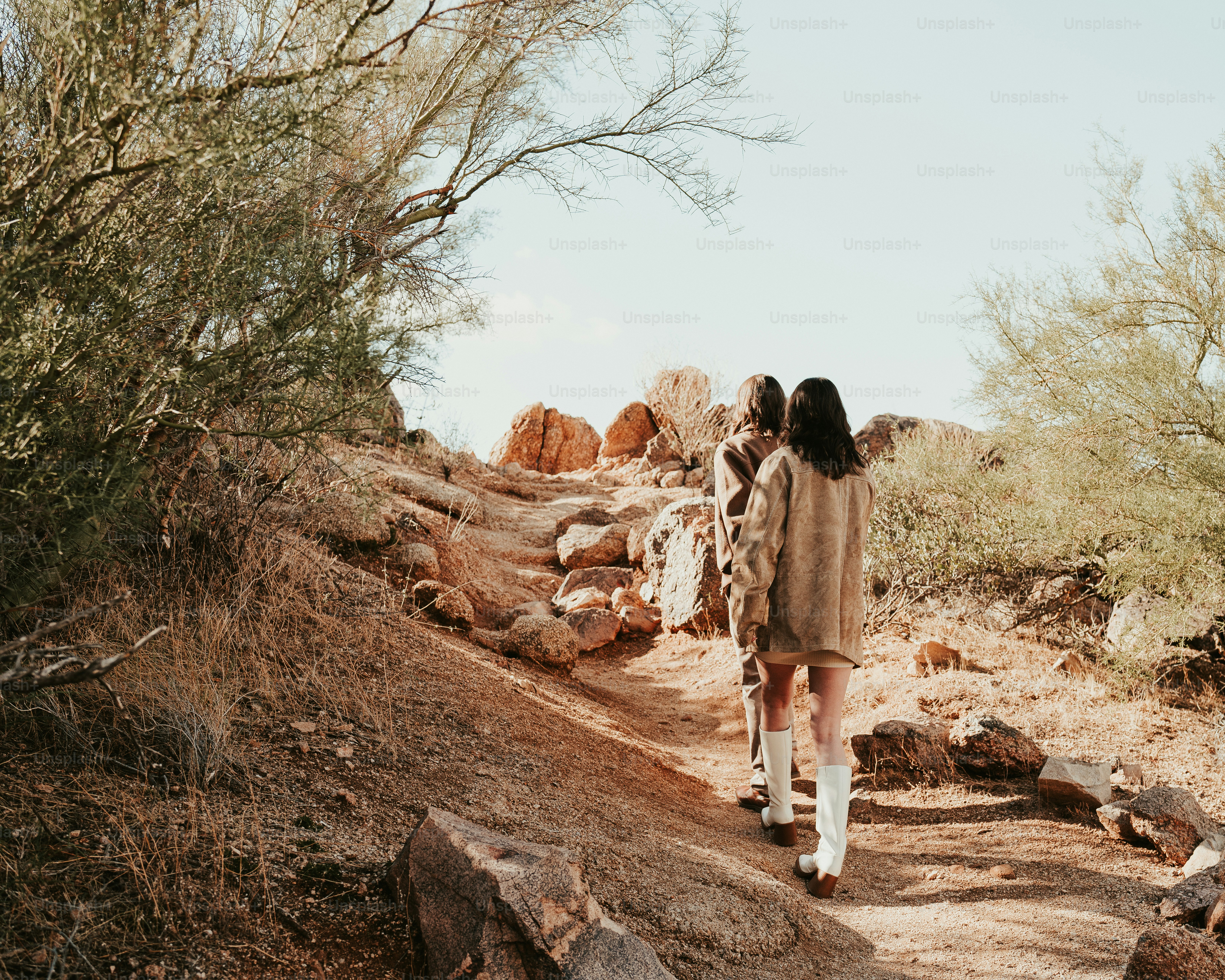 A couple of people walking down a dirt road