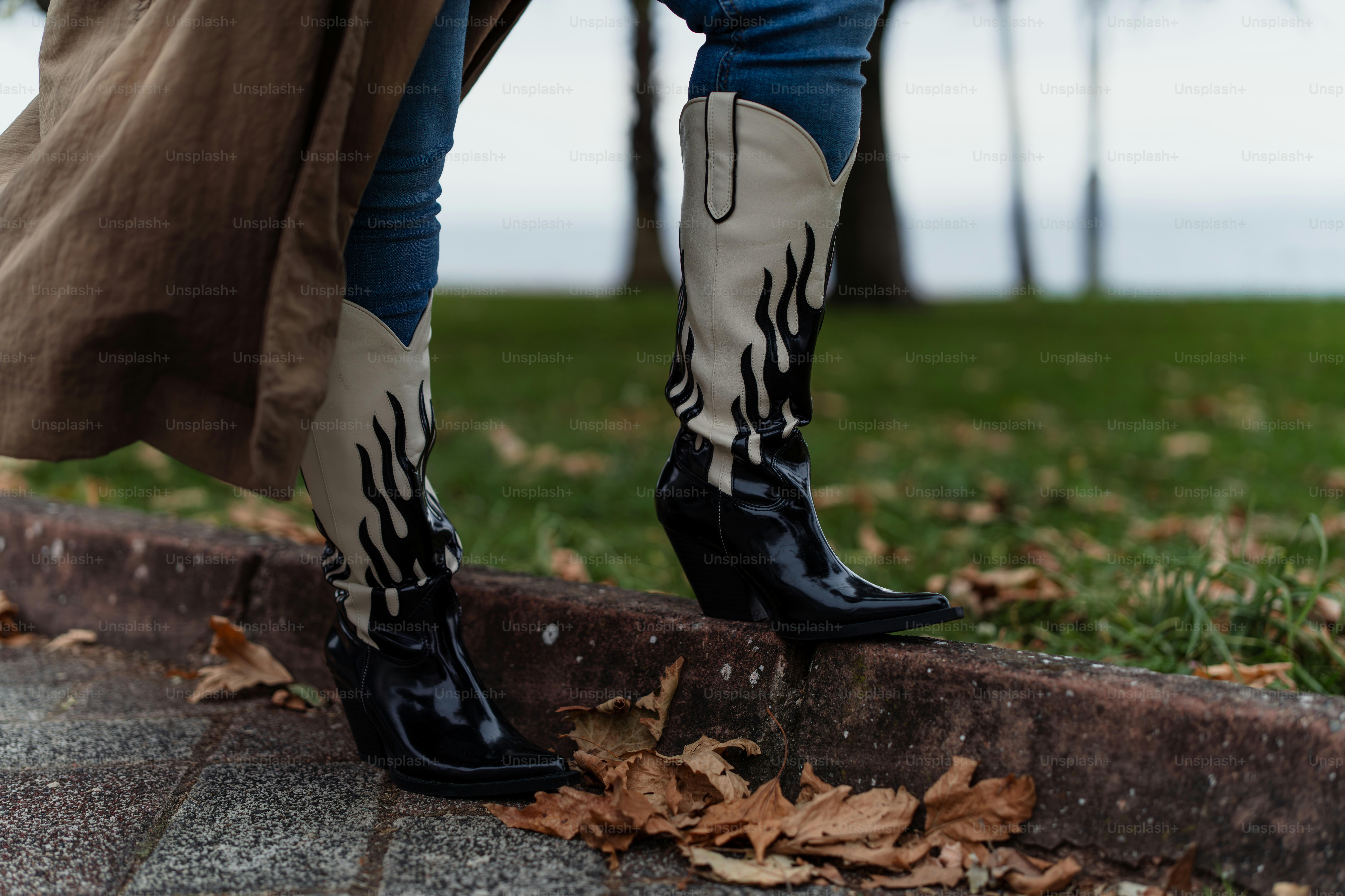 A woman in black boots standing on a sidewalk photo – Fashion Image on ...