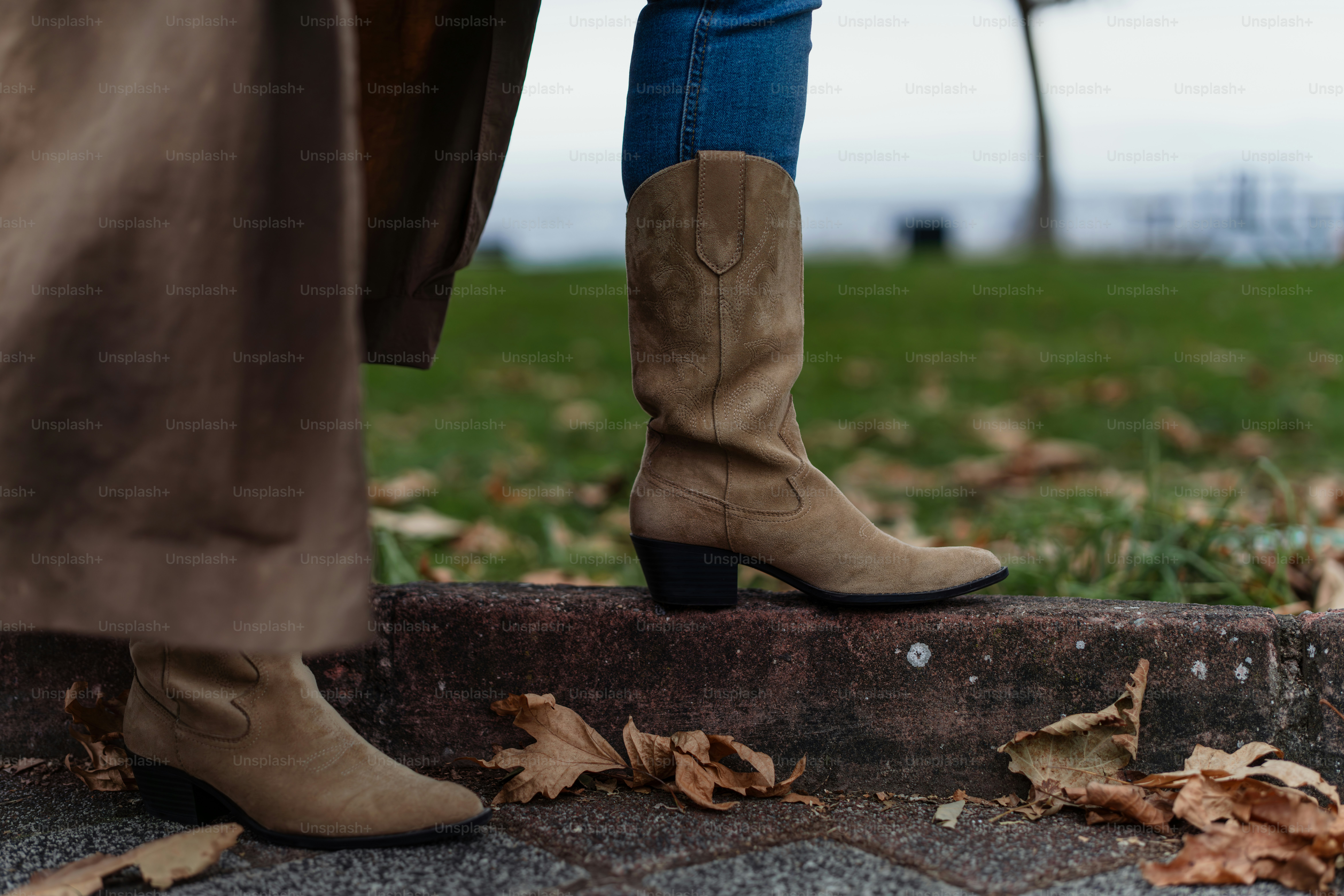 A woman in black boots standing on a sidewalk photo – Fashion Image on ...
