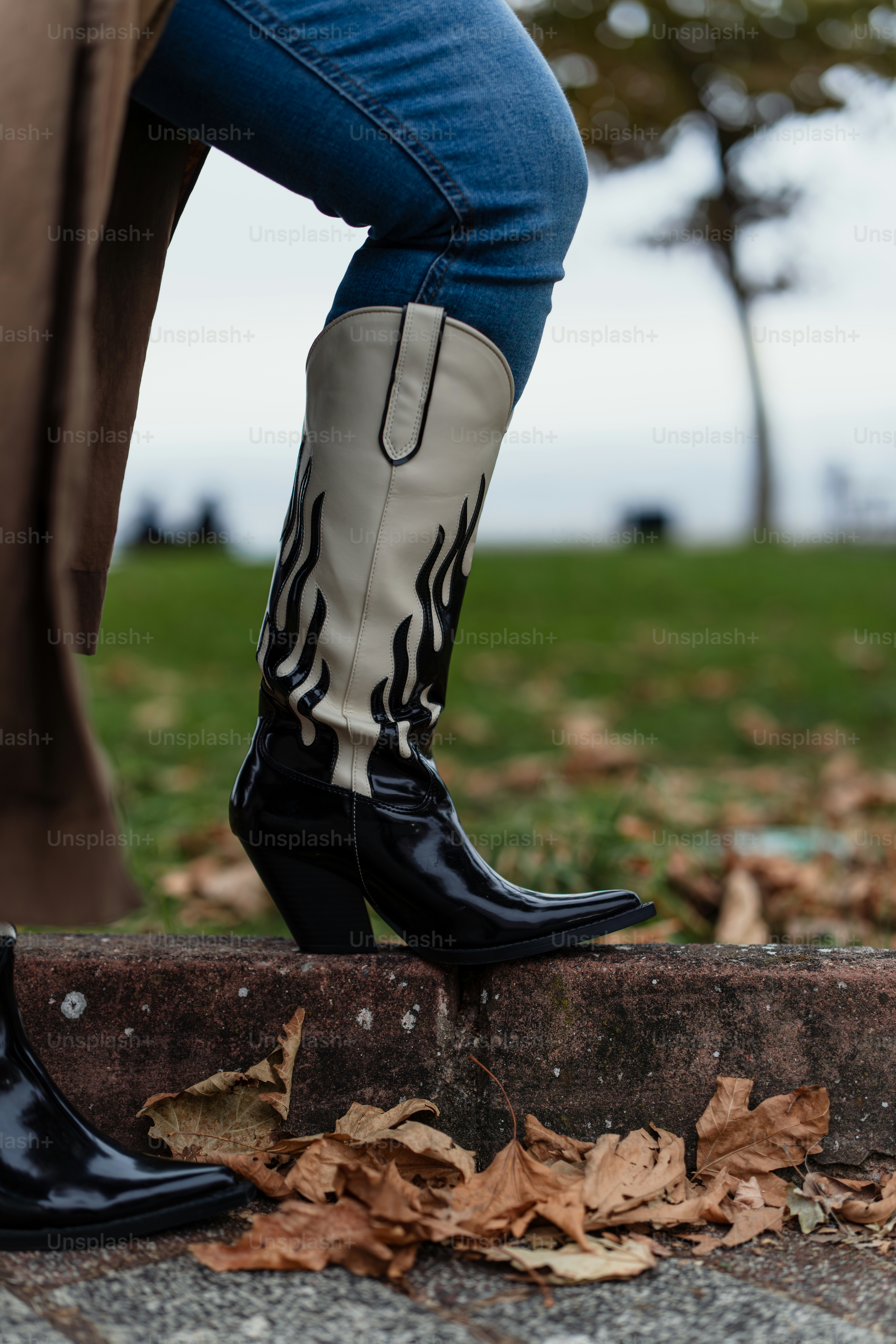 A woman in black boots standing on a sidewalk photo – Fashion Image on ...