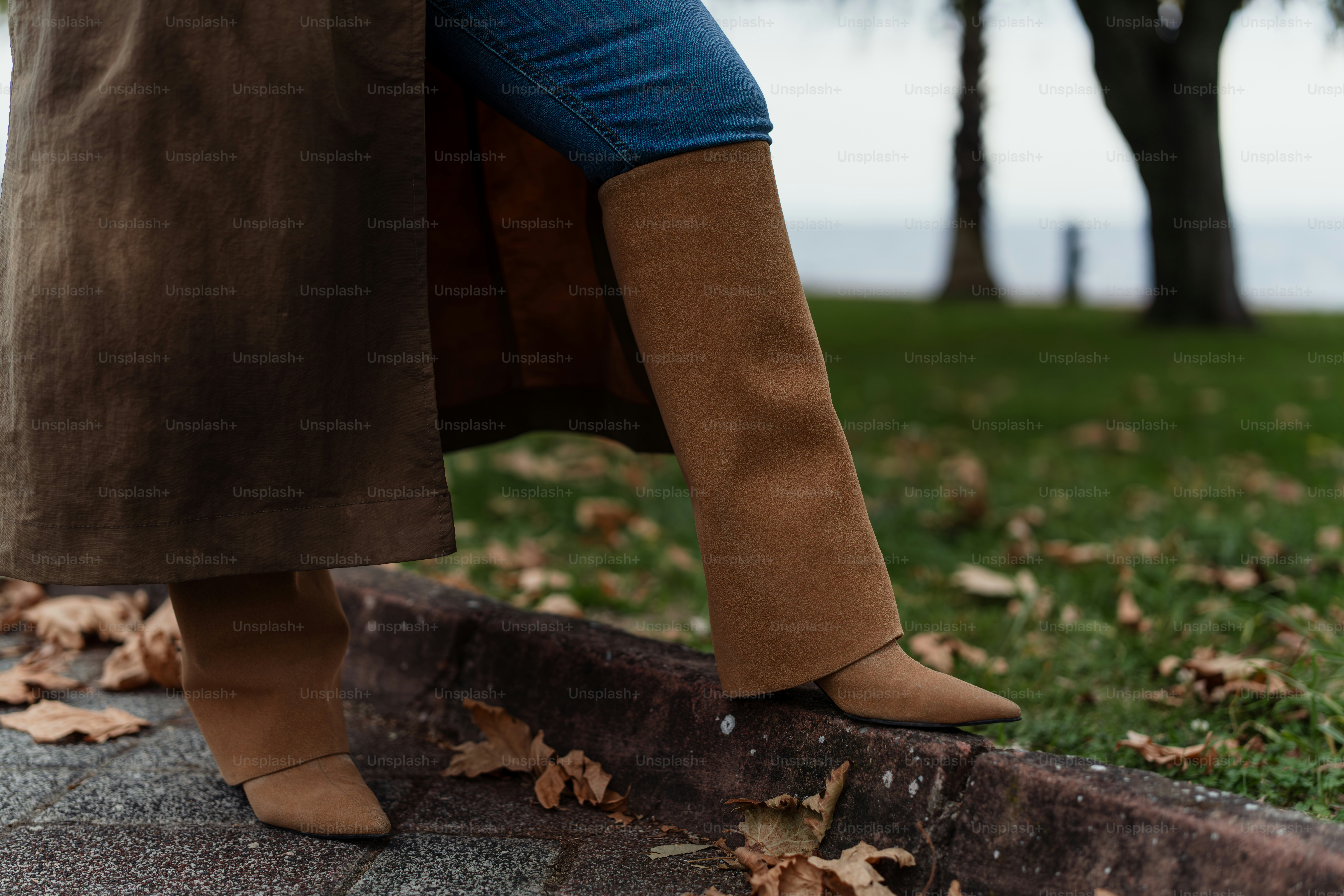 A woman in black boots standing on a sidewalk photo – Fashion Image on ...