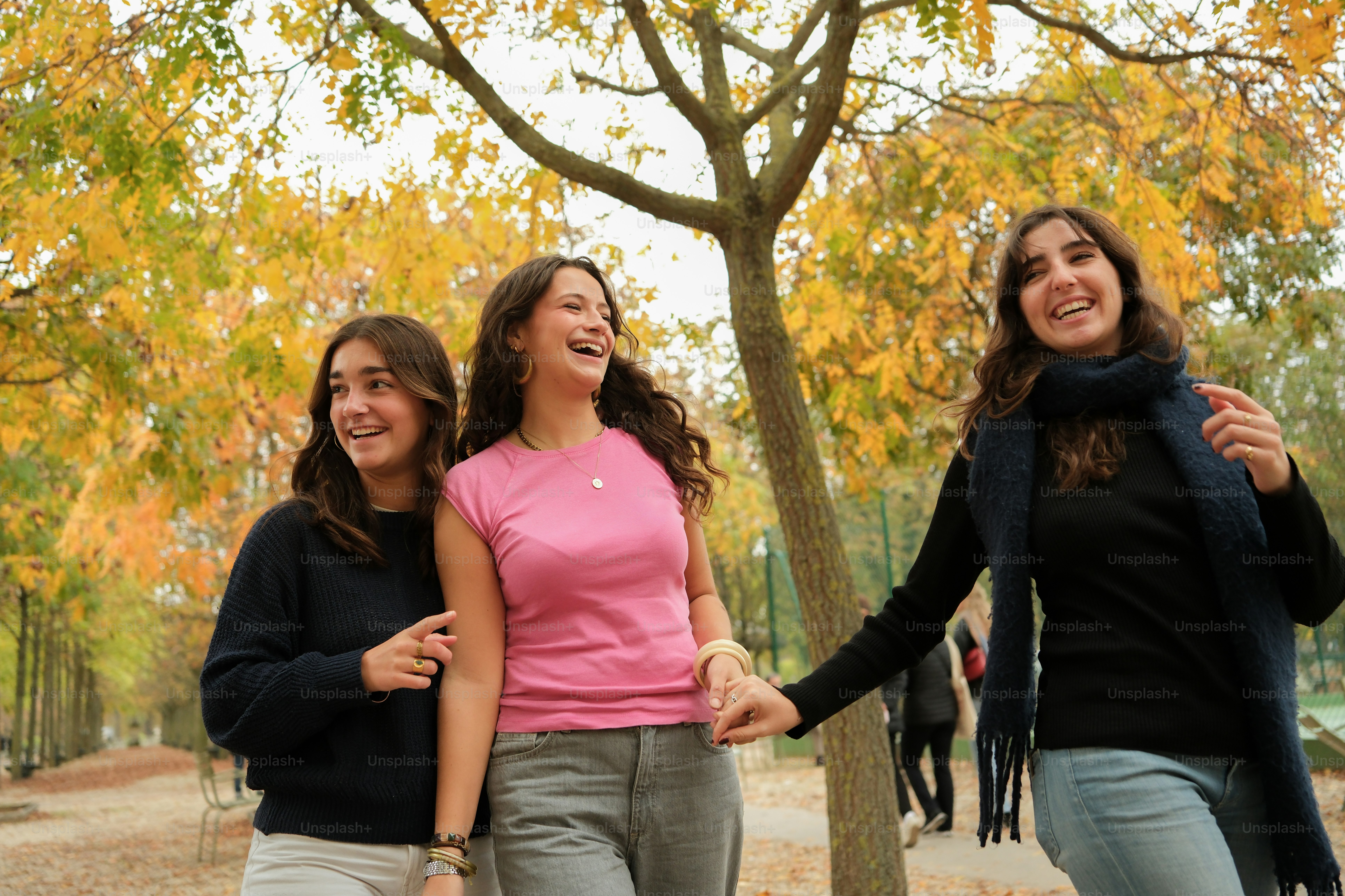 Three young women walking in a park holding hands