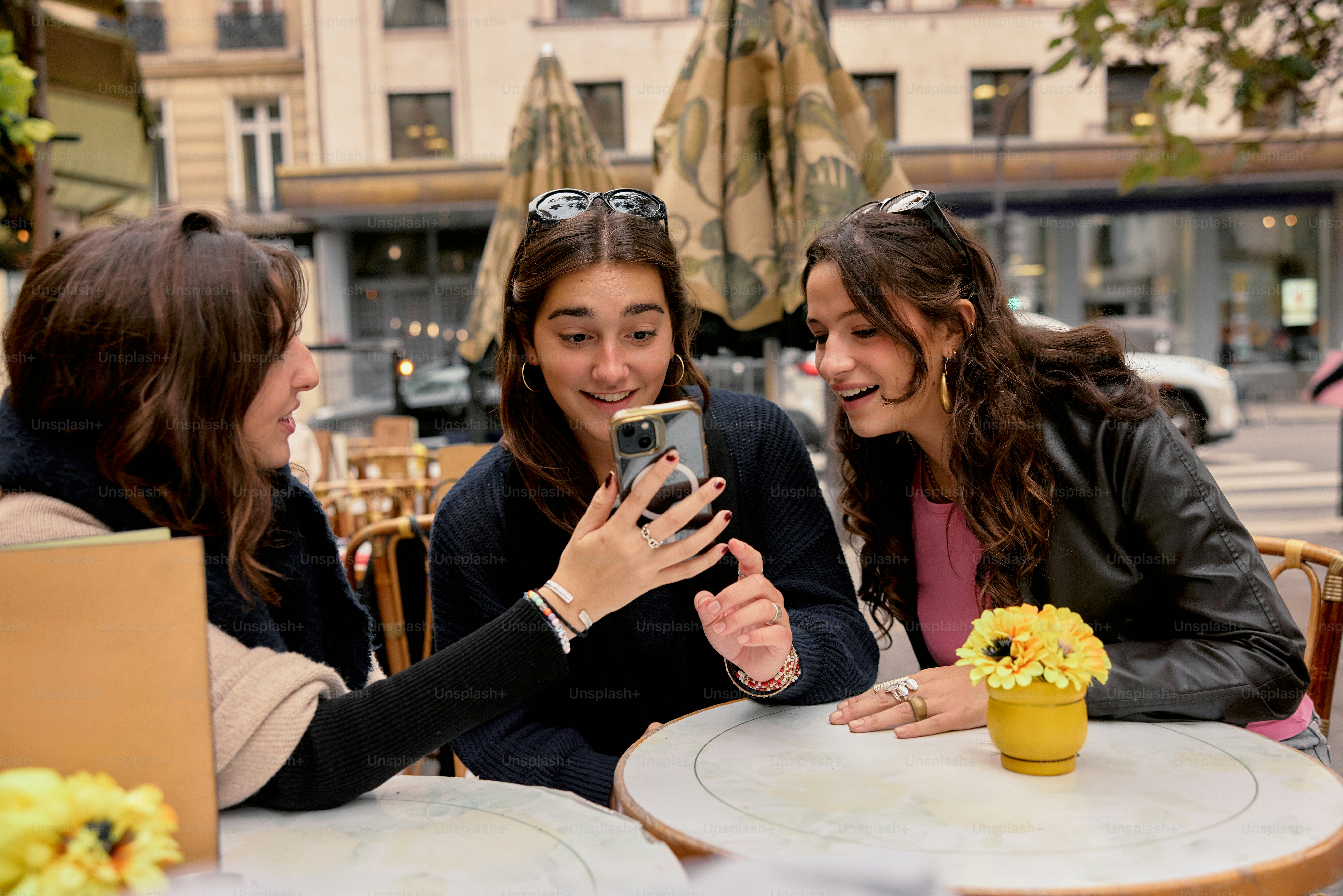 A group of women sitting at a table with a cell phone