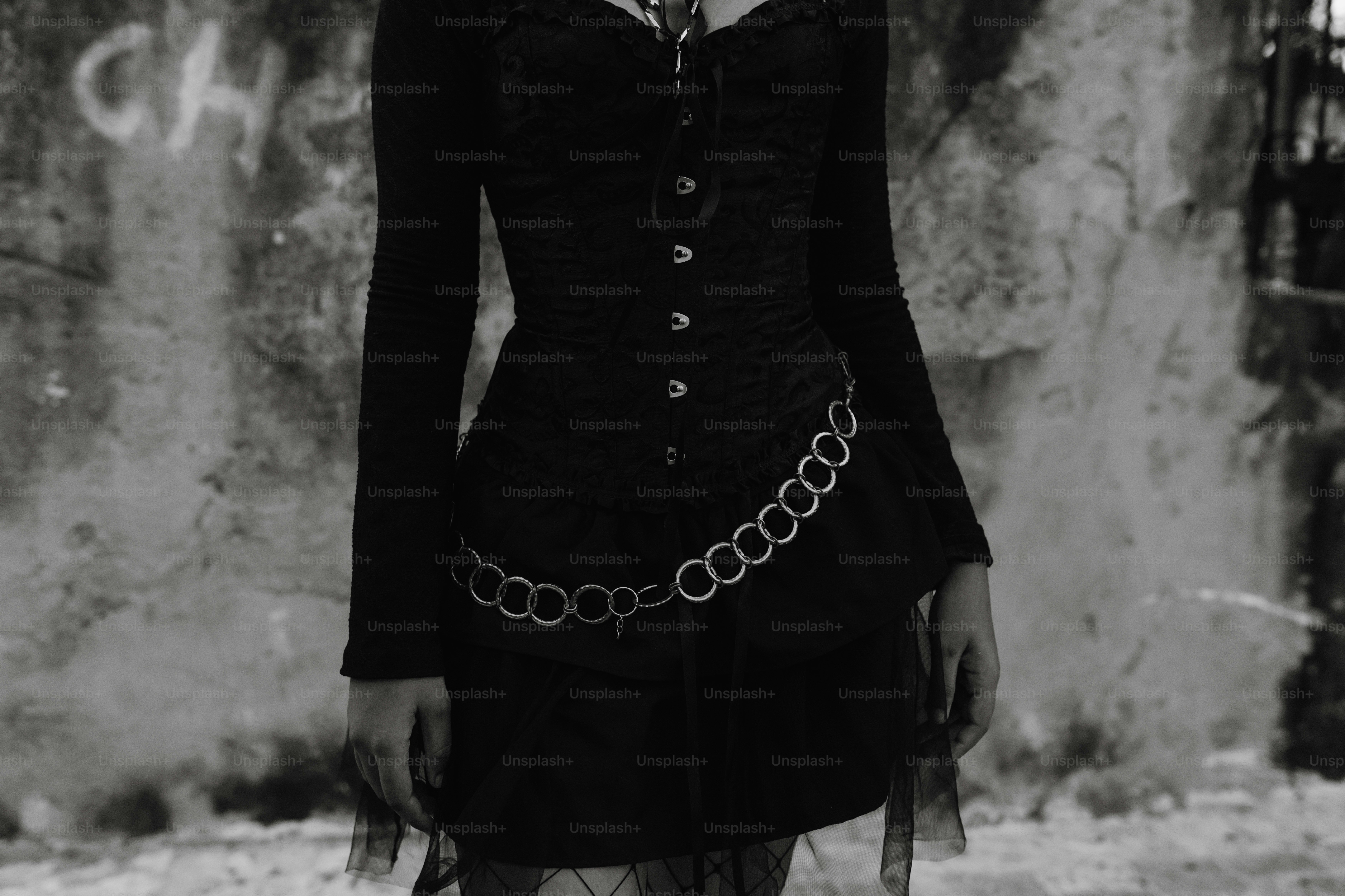 A woman in a black dress with a chain around her waist