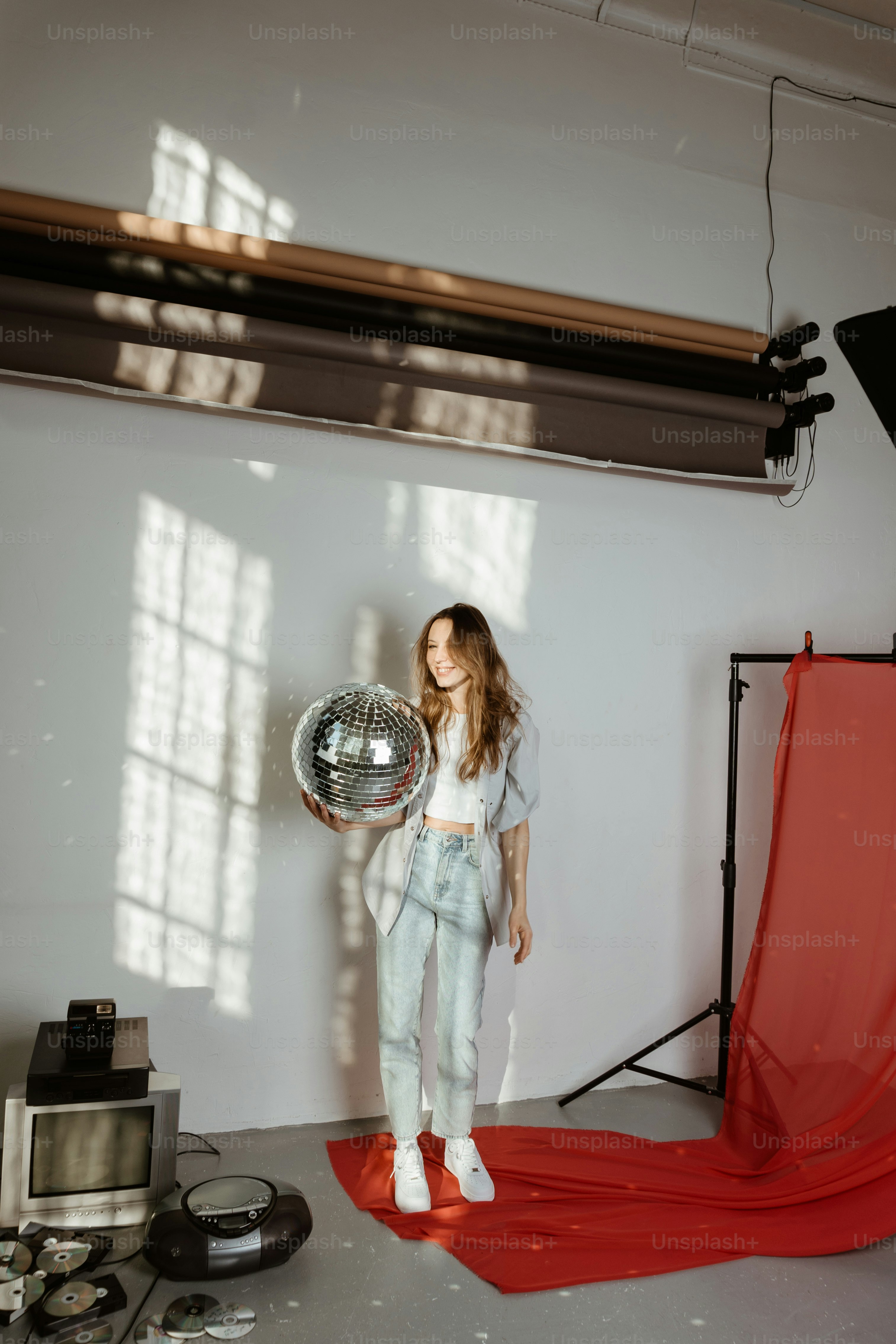 Ein junges Mädchen hält eine Discokugel in einem Studio