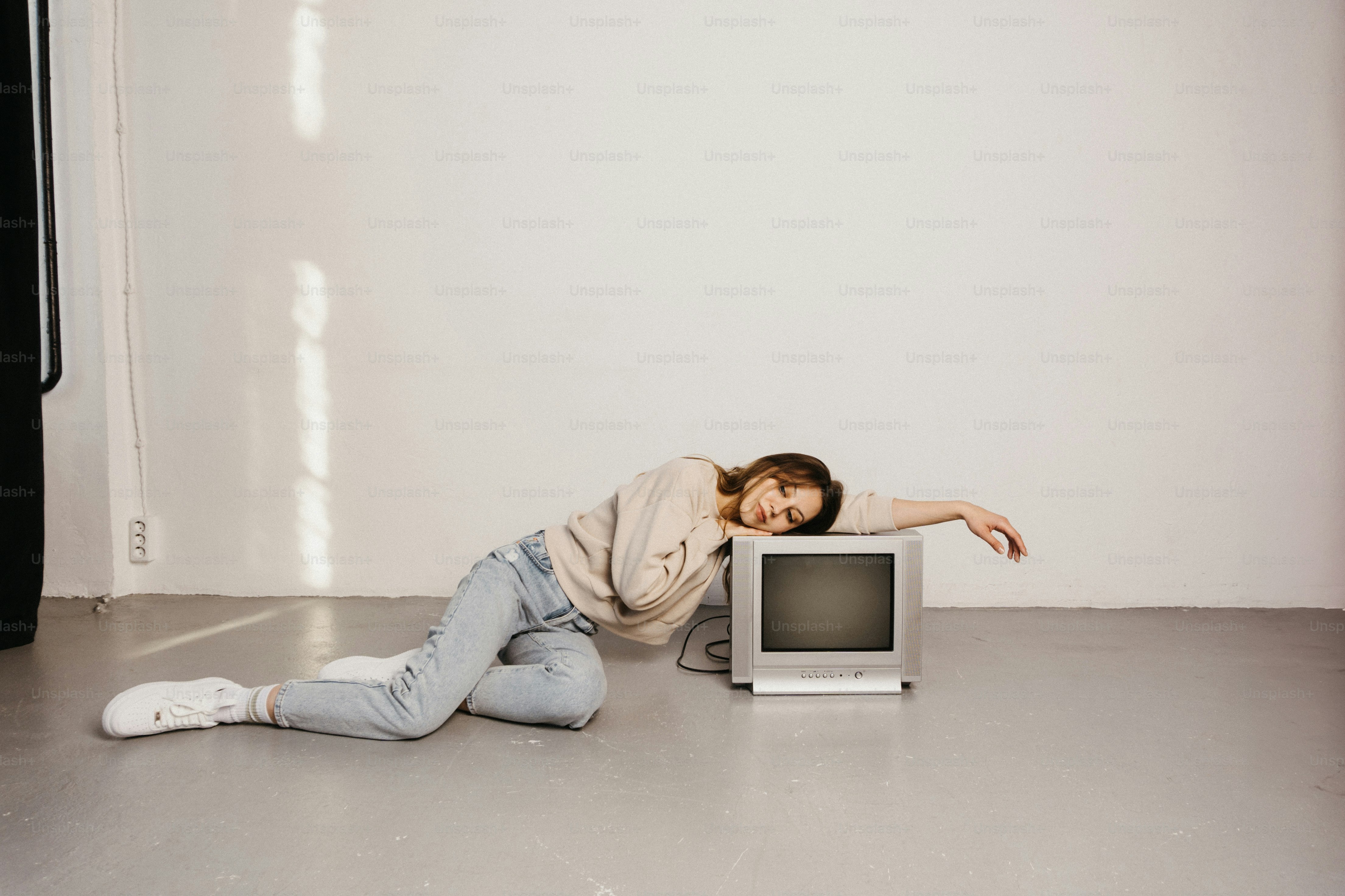 Eine Frau, die vor einem Fernseher auf dem Boden liegt
