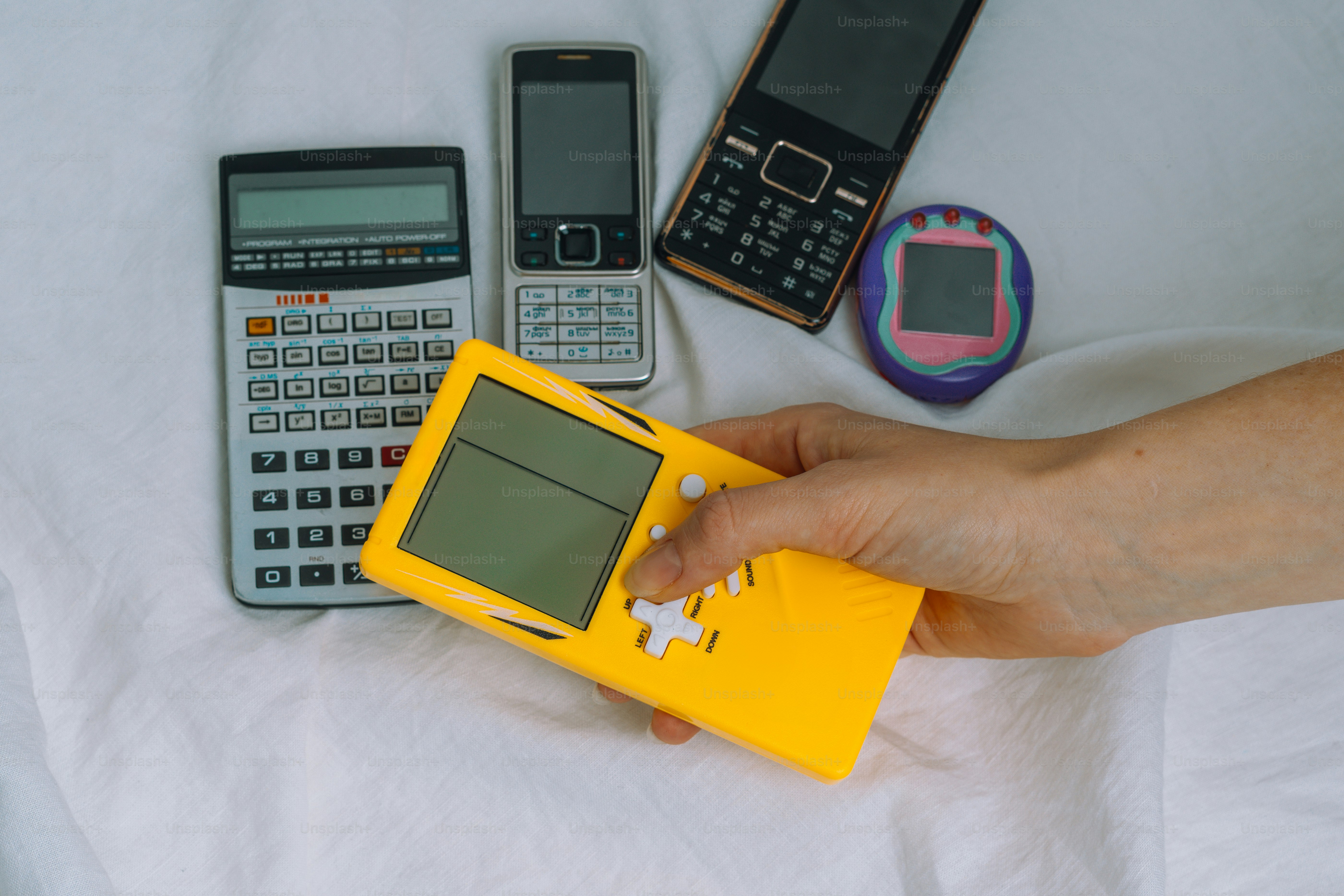 A person's hand holding a small yellow device