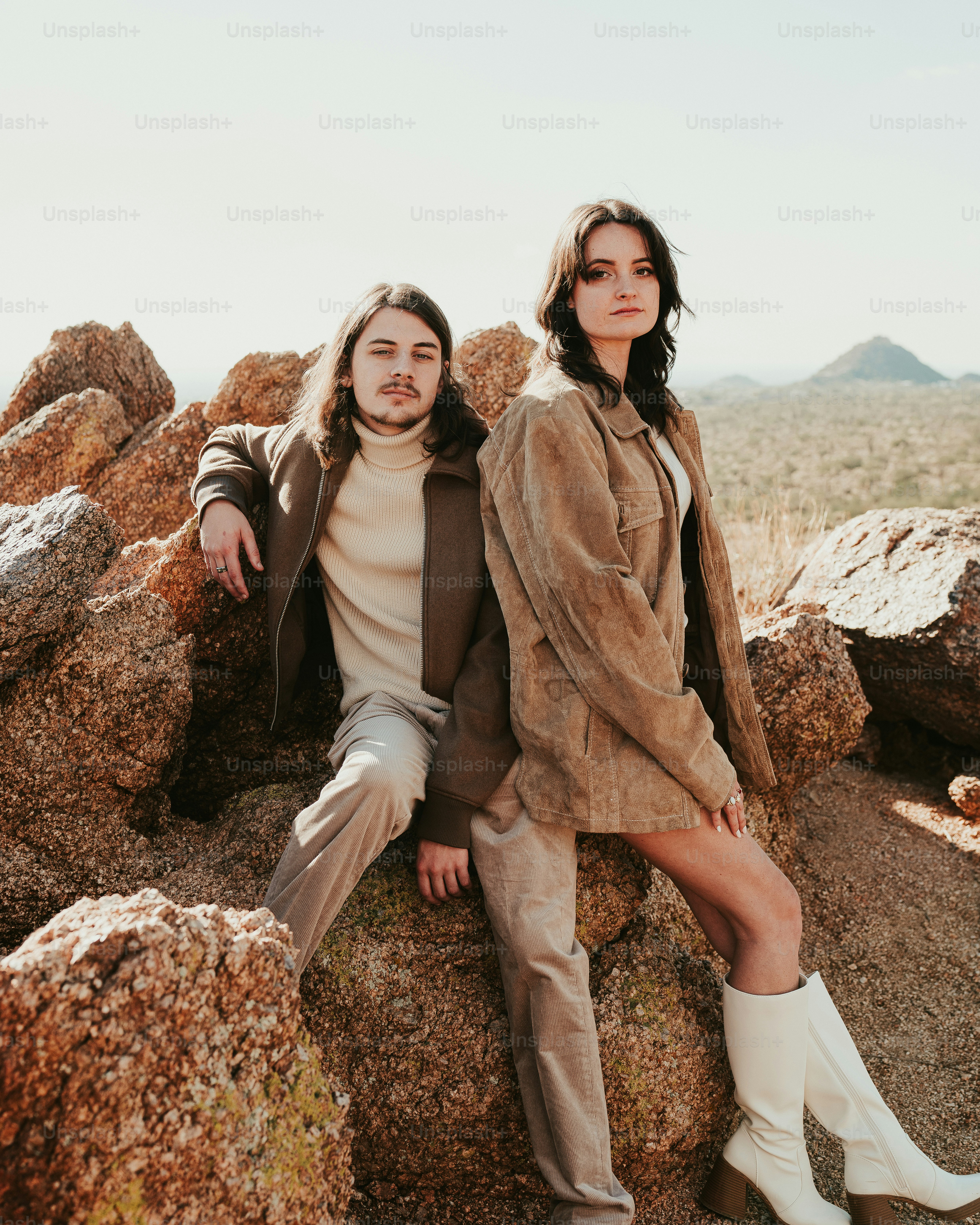 A man and a woman sitting on rocks in the desert