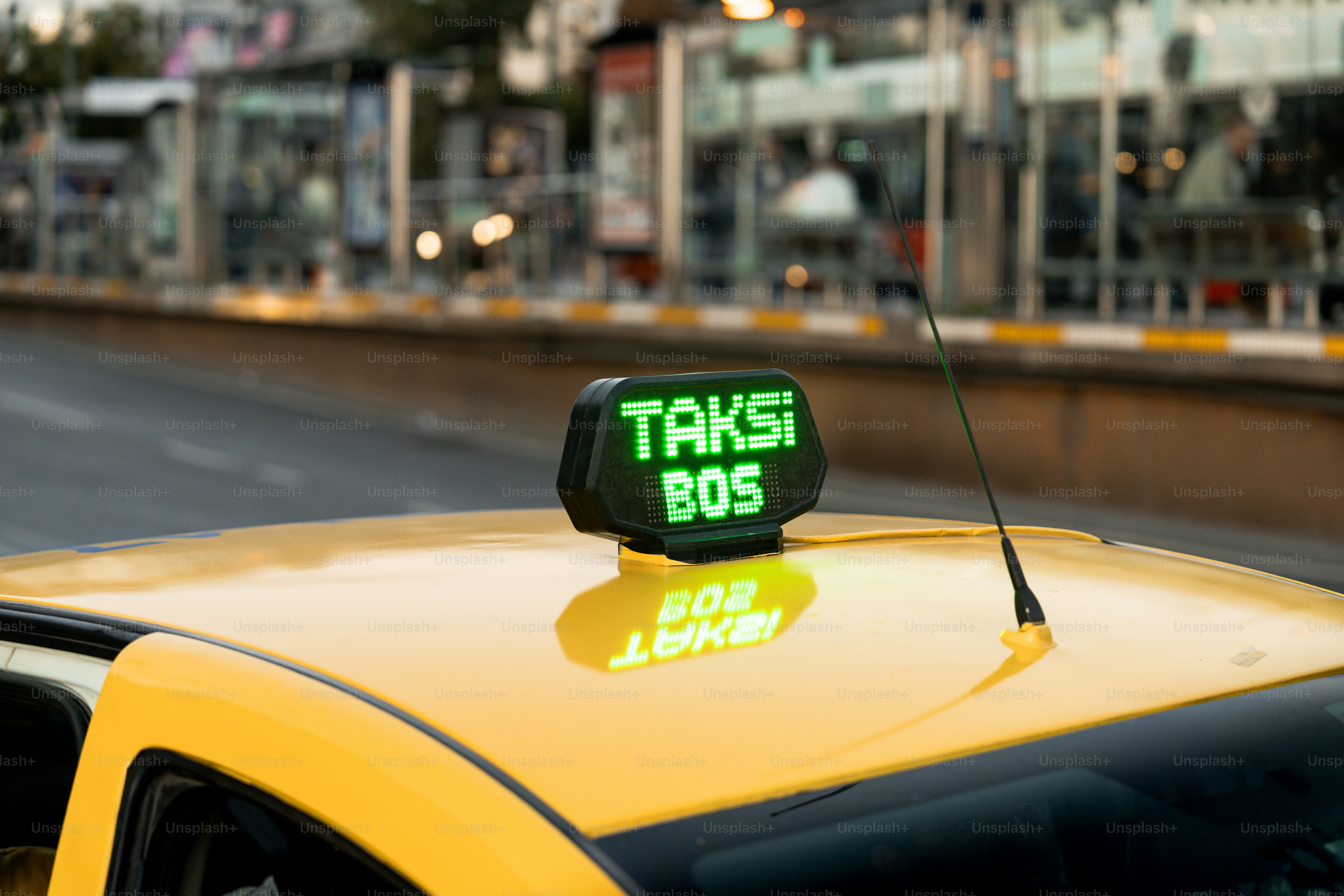 Taksi kuning dengan tanda hijau di atasnya