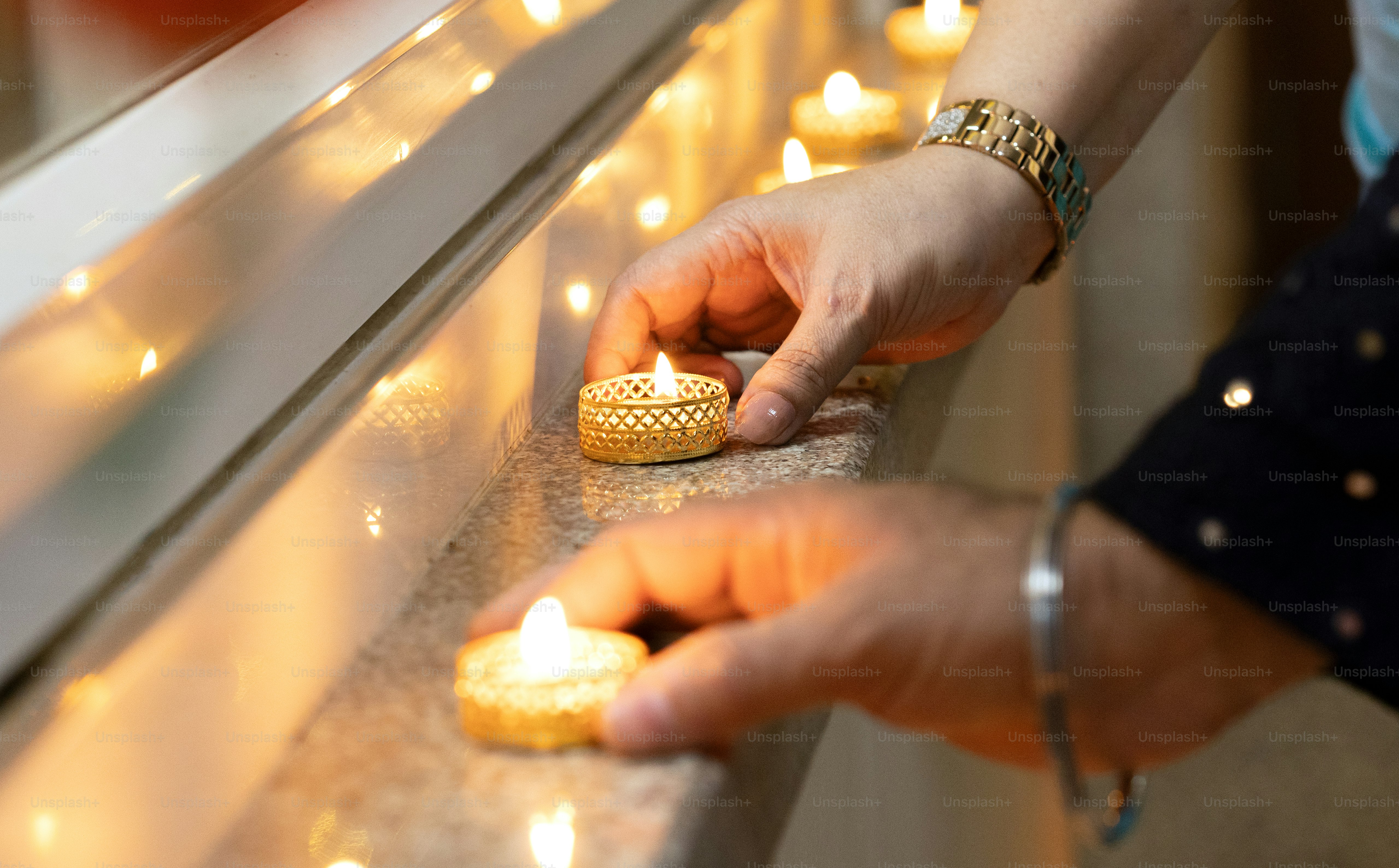 A person lighting candles on a window sill