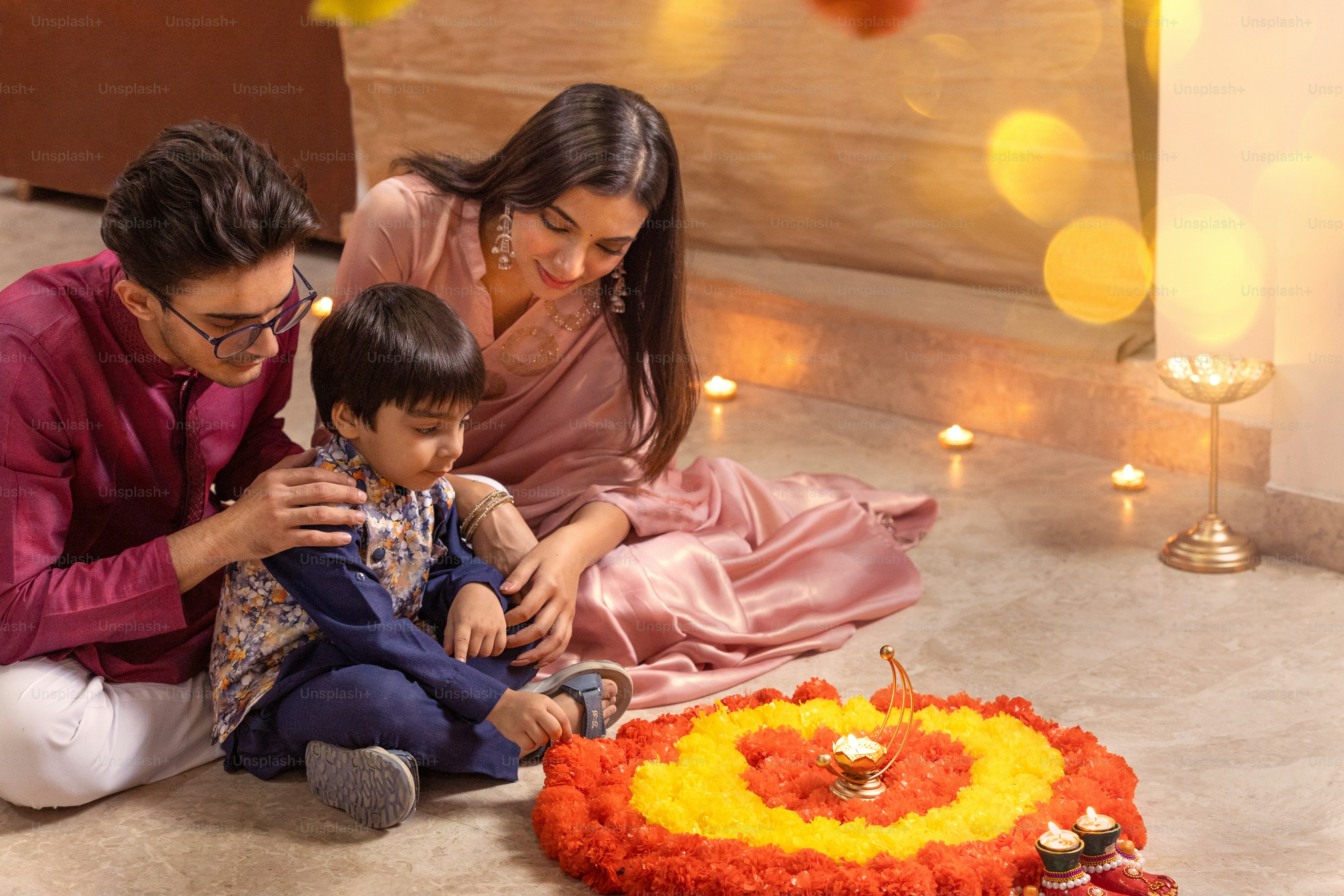 A family sitting on the floor in front of a flower arrangement
