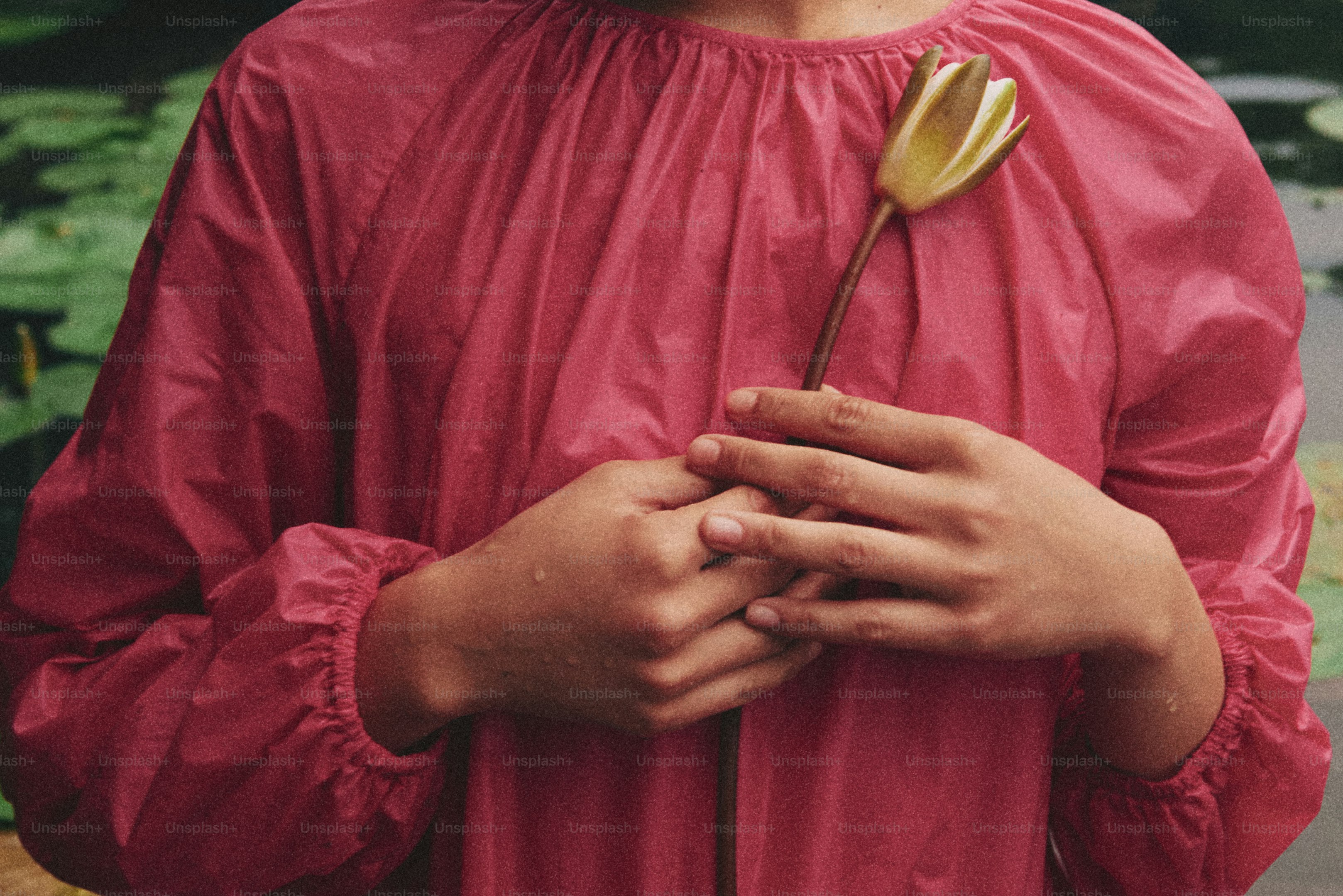 Ein kleiner Junge in einem roten Hemd hält eine Blume in der Hand