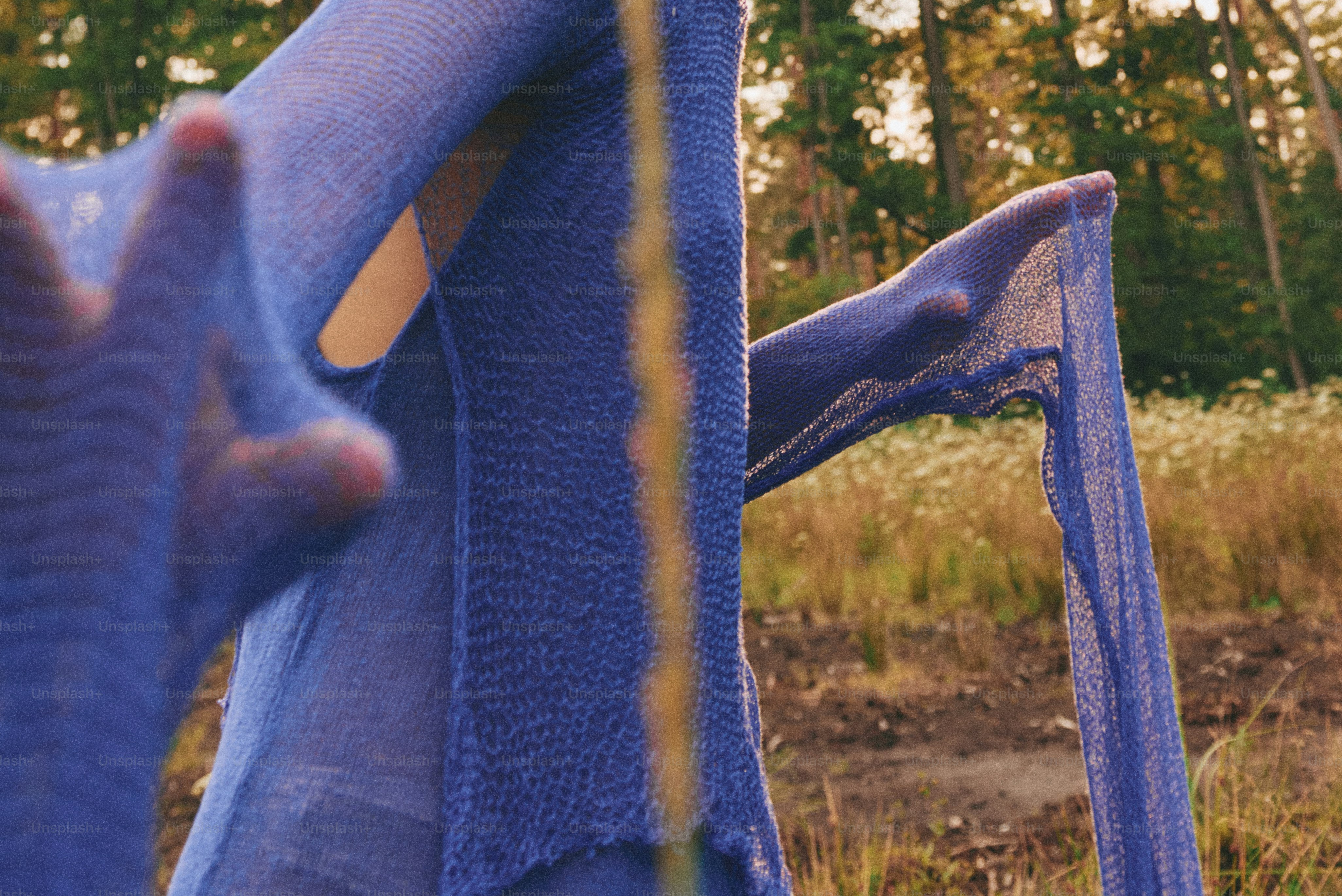 A blue chair in a field with trees in the background