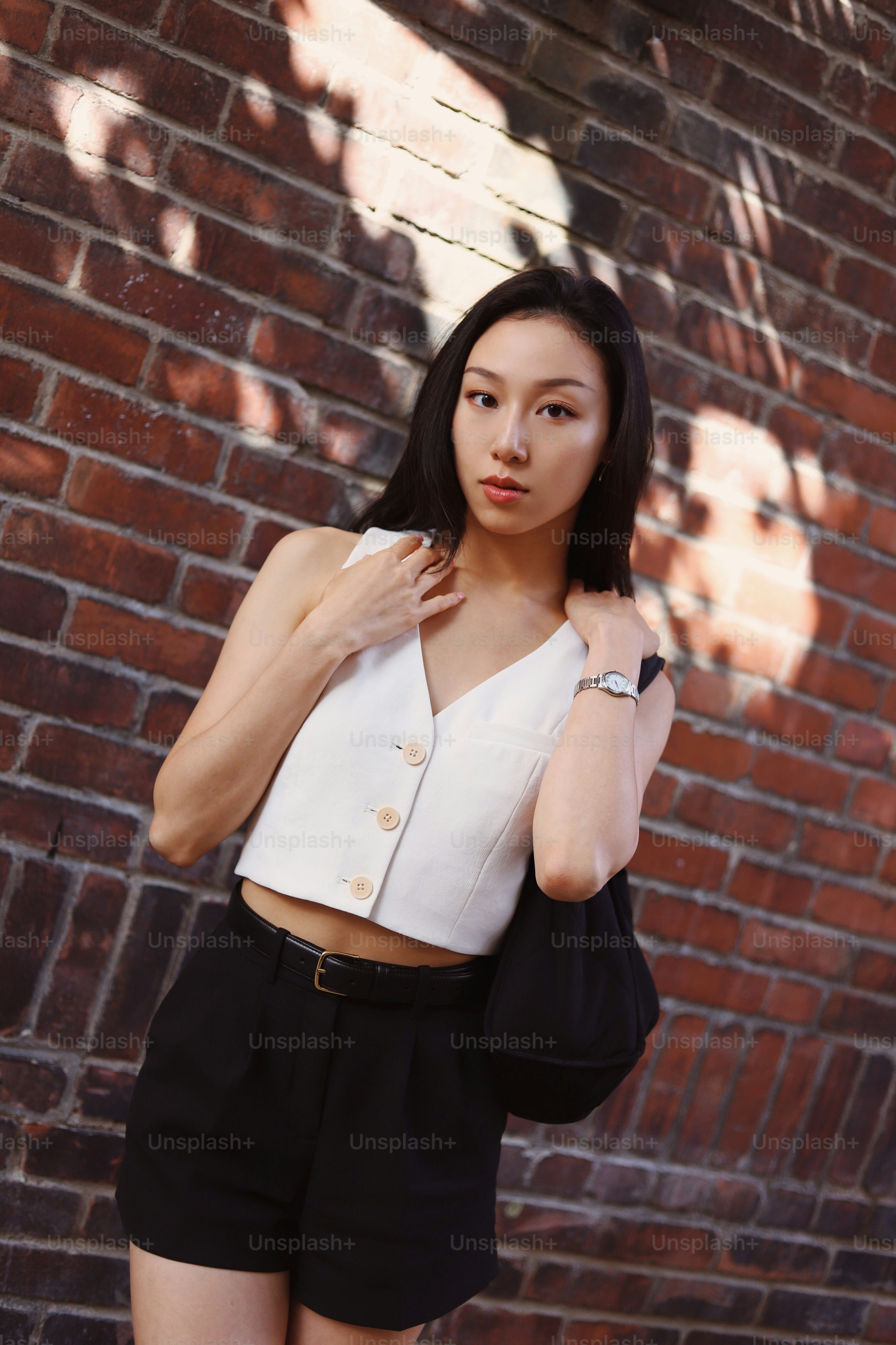 A woman standing in front of a brick wall photo – Pretty woman Image on ...