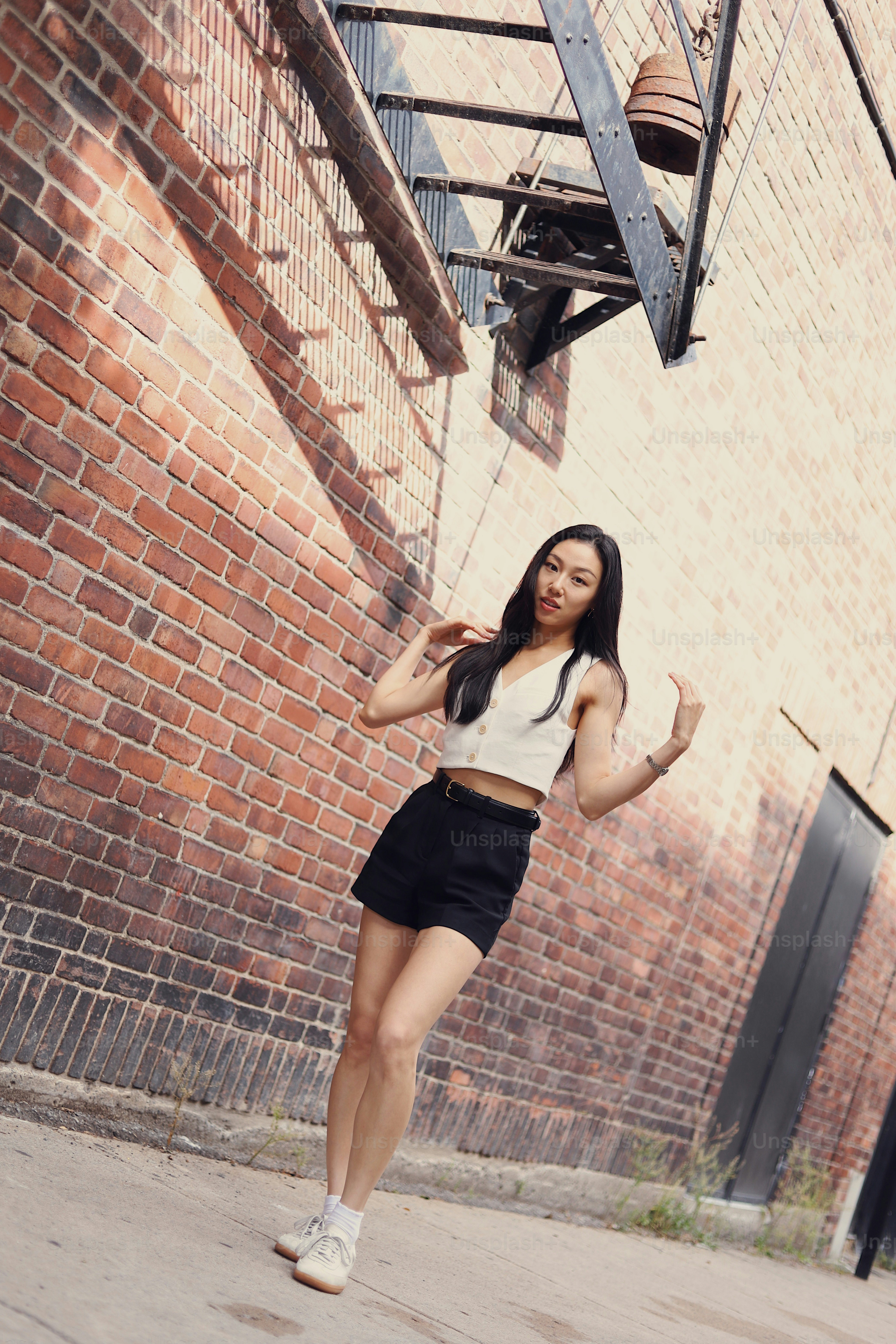 A woman standing on a sidewalk in front of a brick building photo ...