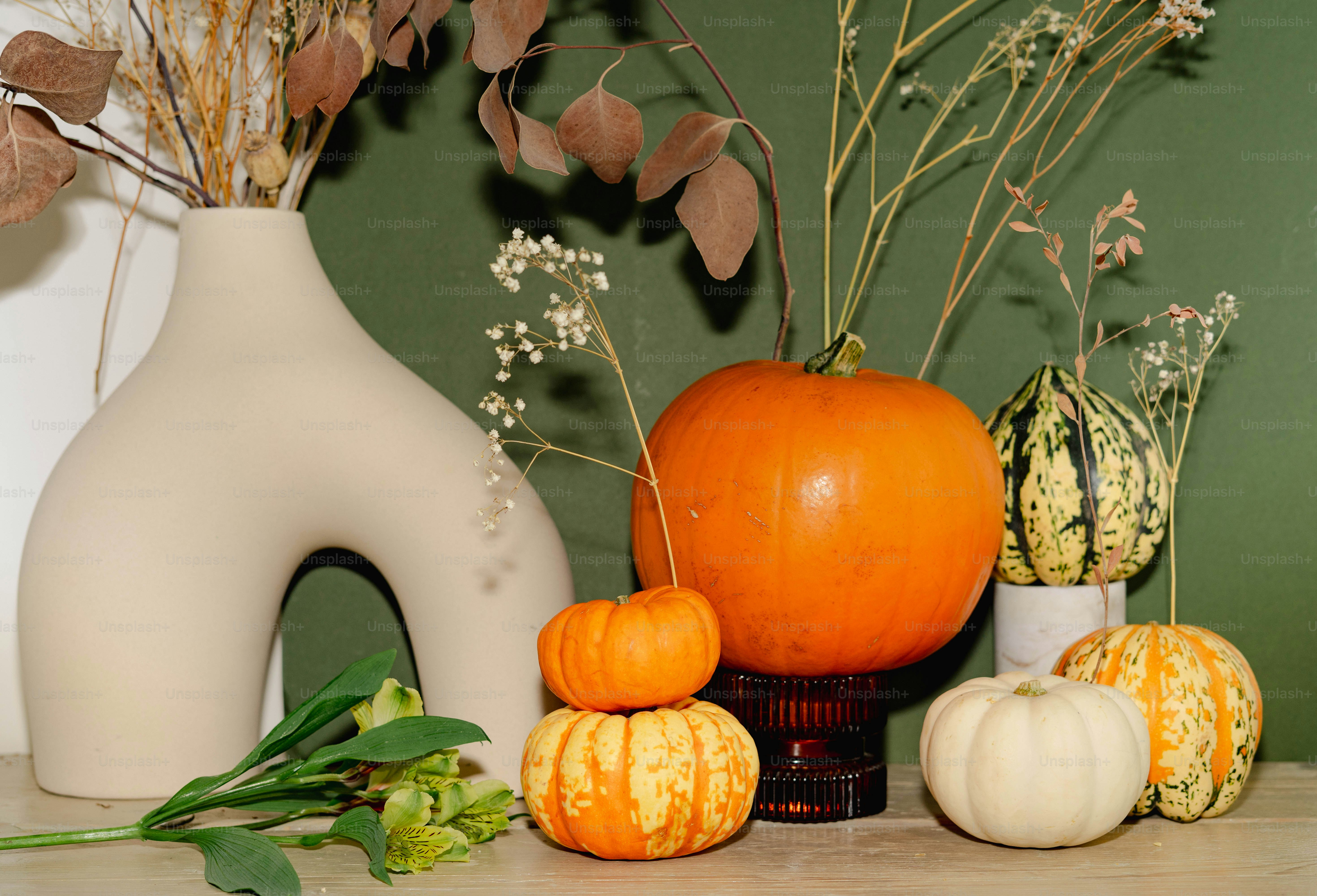 A table topped with a vase filled with flowers and pumpkins