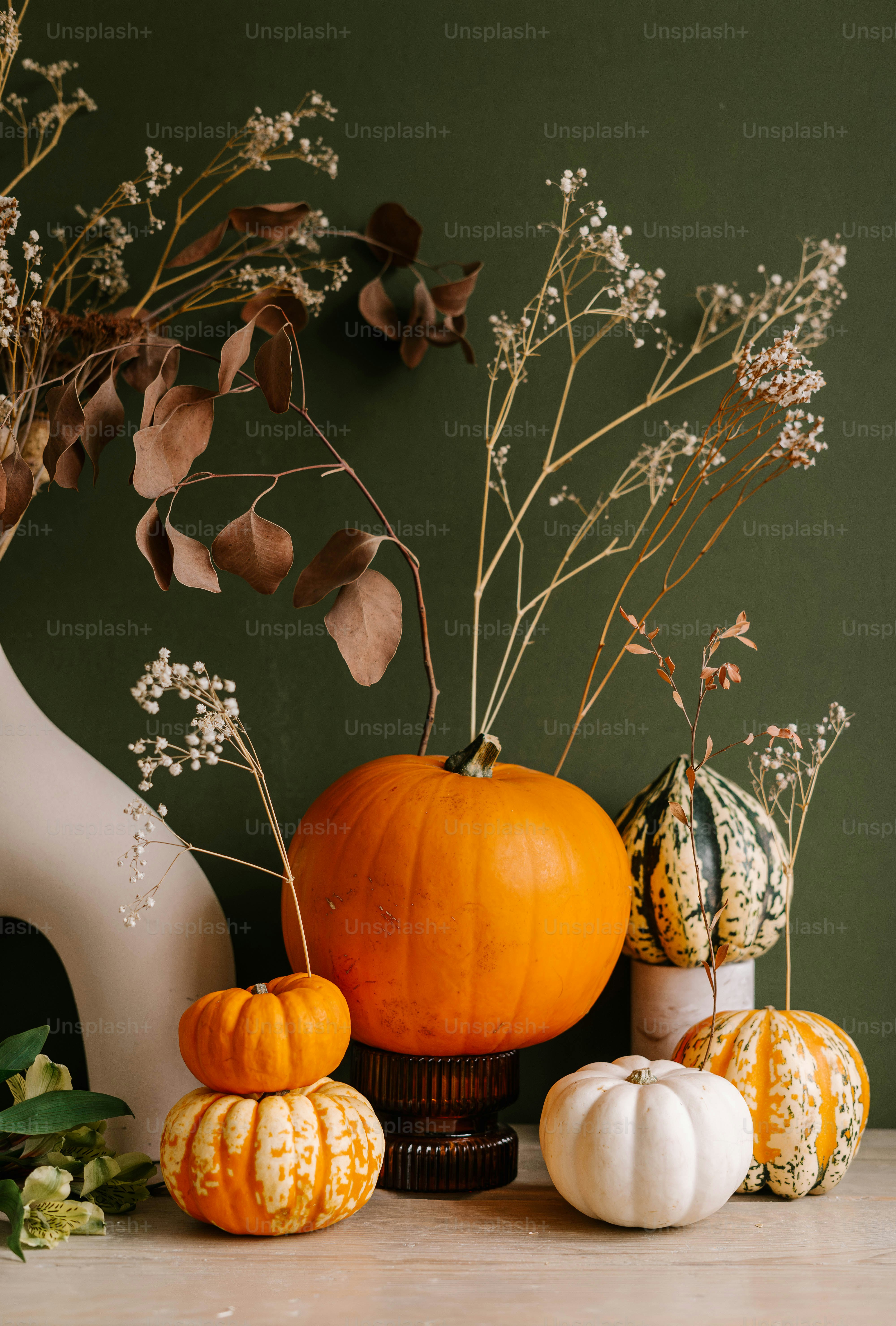 Uma mesa coberta com um vaso cheio de flores e abóboras