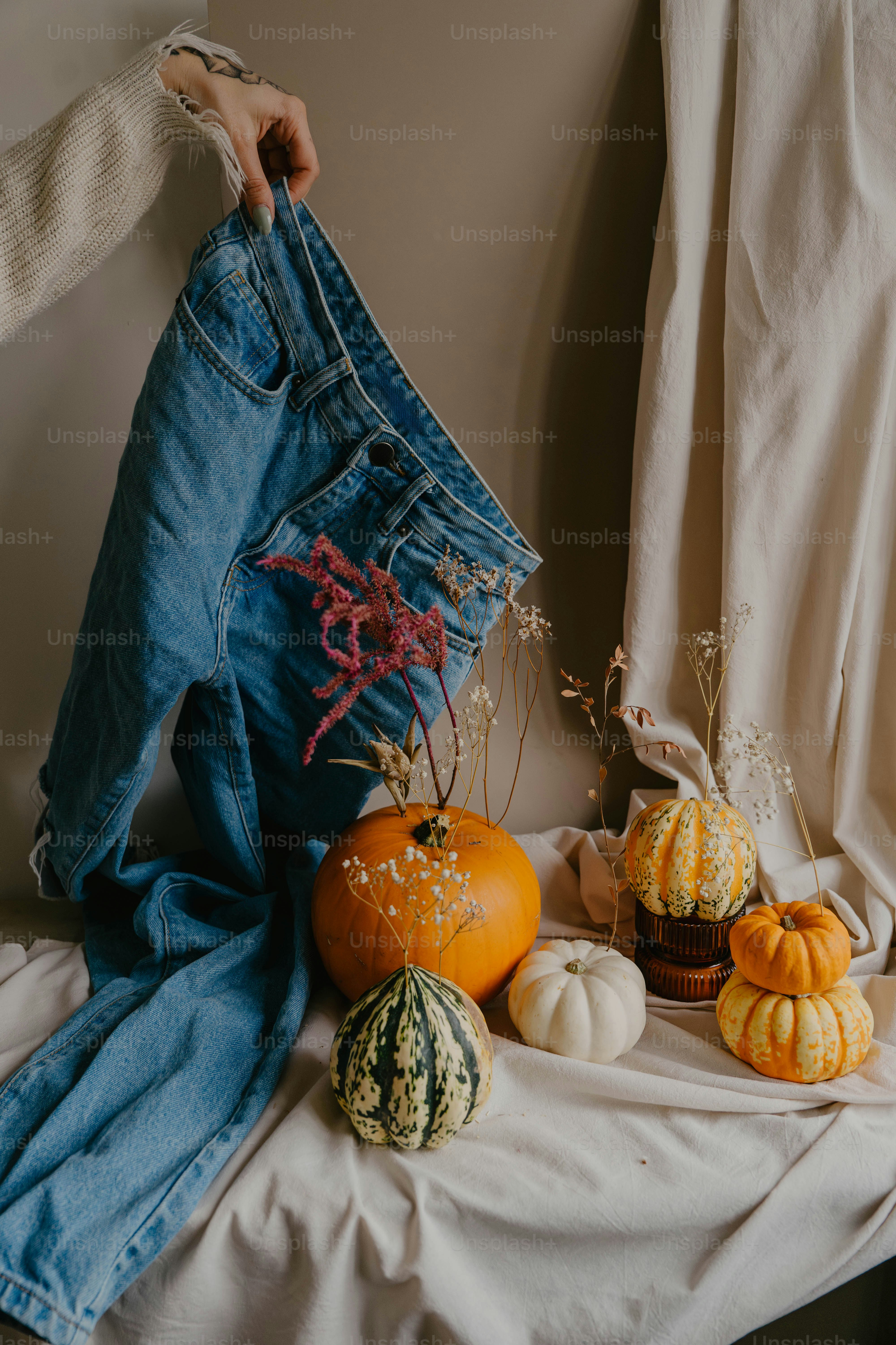 A pair of jeans hanging on a clothes line with pumpkins and gourds