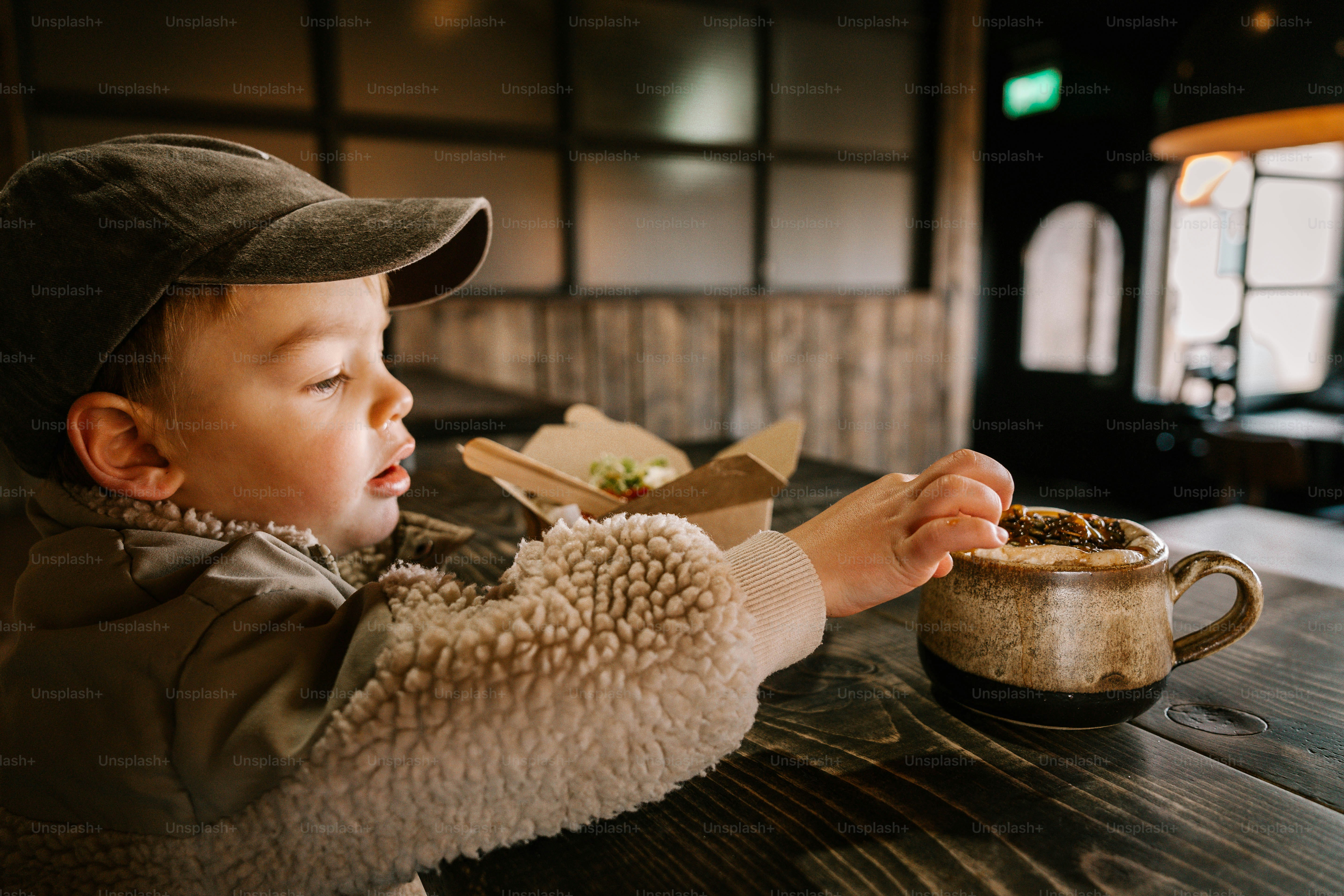 Um garotinho sentado em uma mesa comendo comida