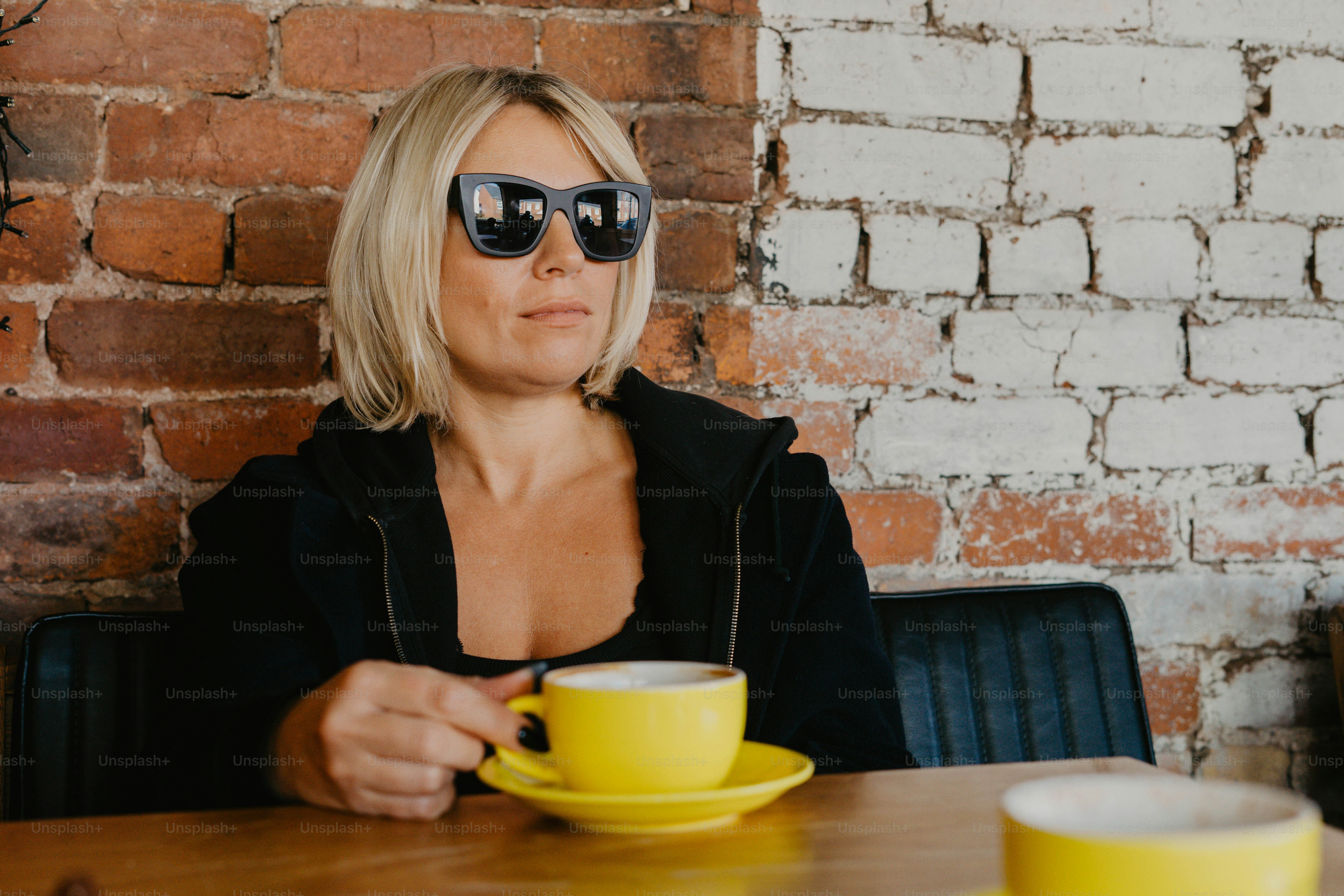 A woman sitting at a table with a cup of coffee