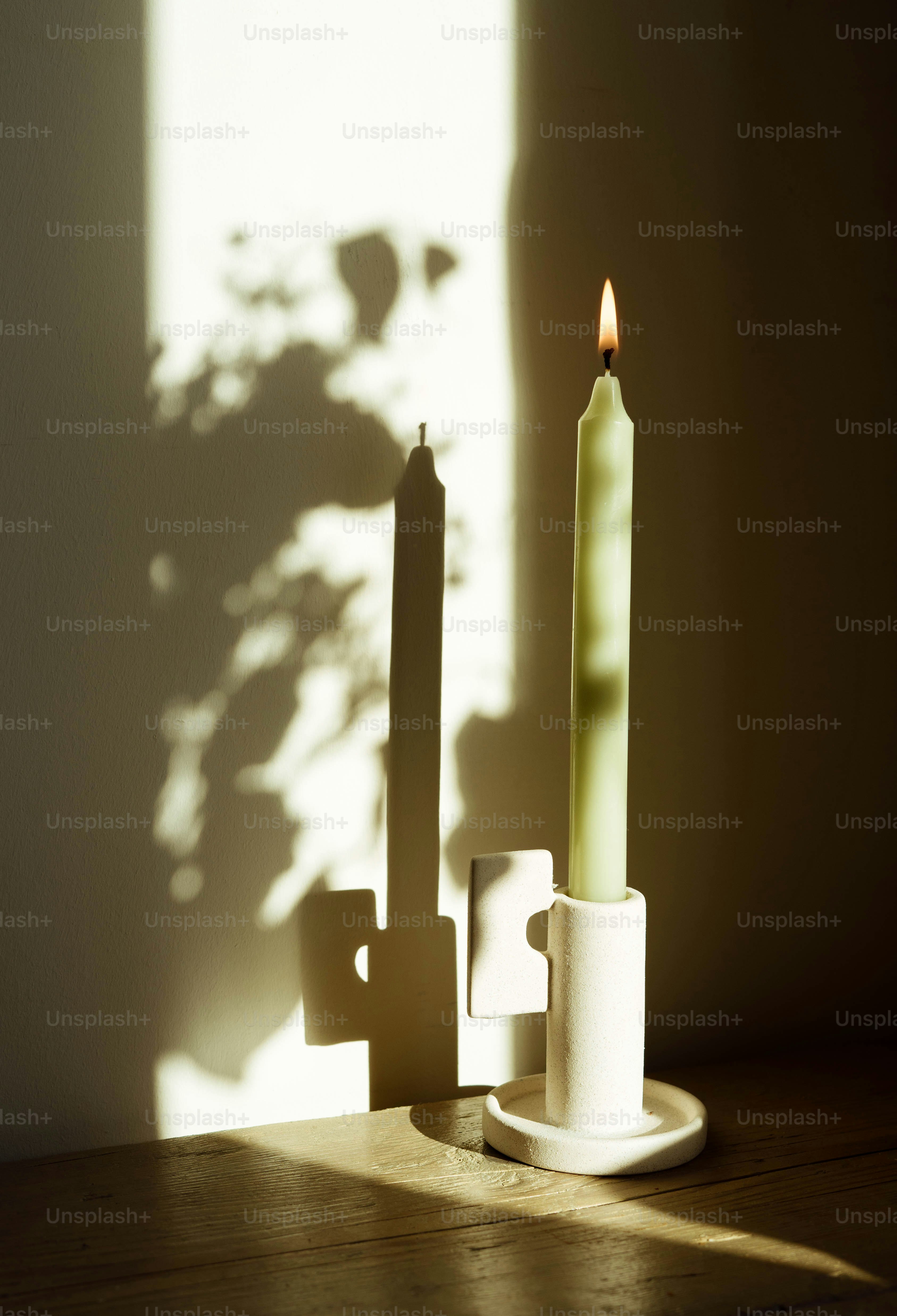 A candle sitting on top of a table next to a cup