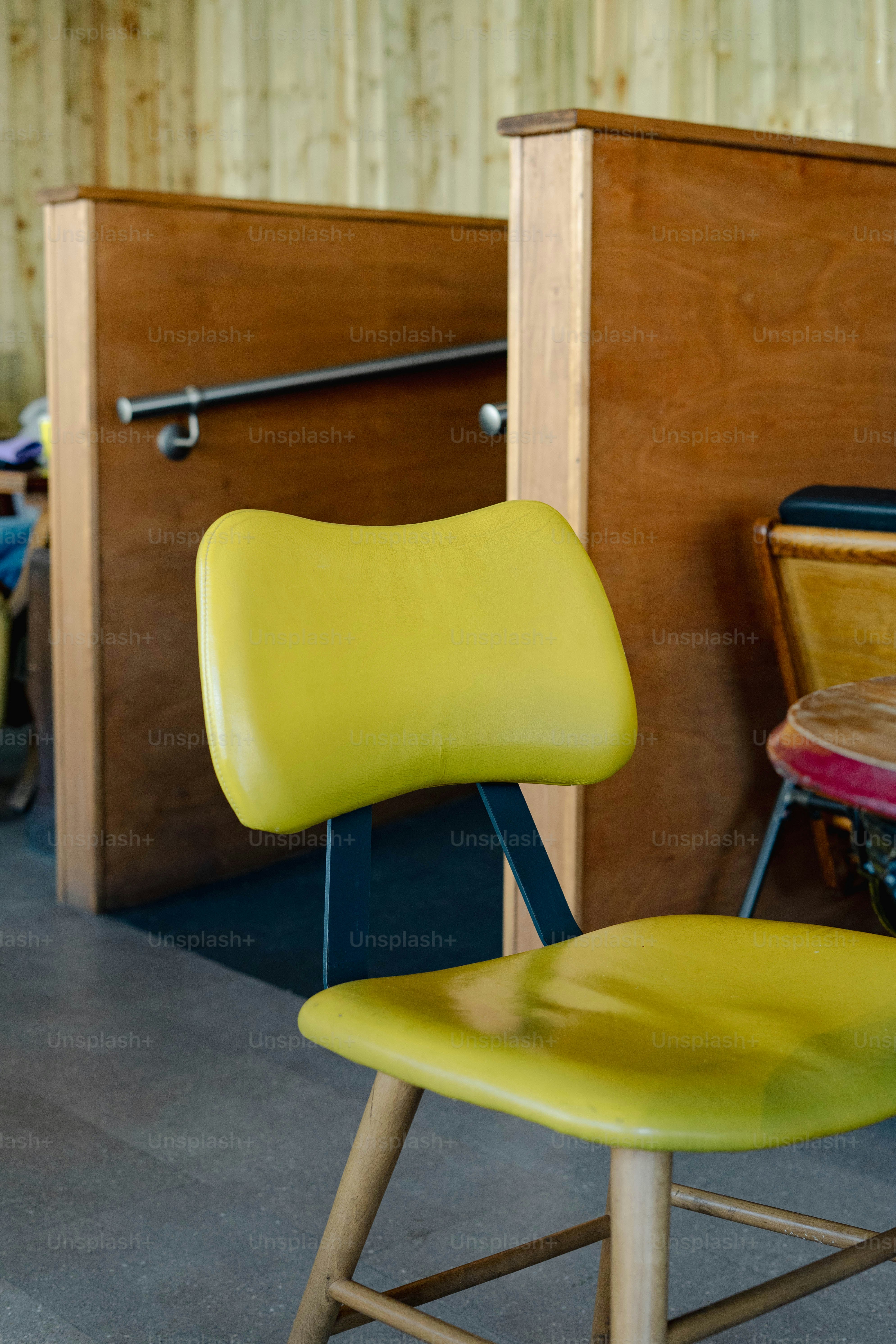 A yellow chair sitting in front of a wooden wall