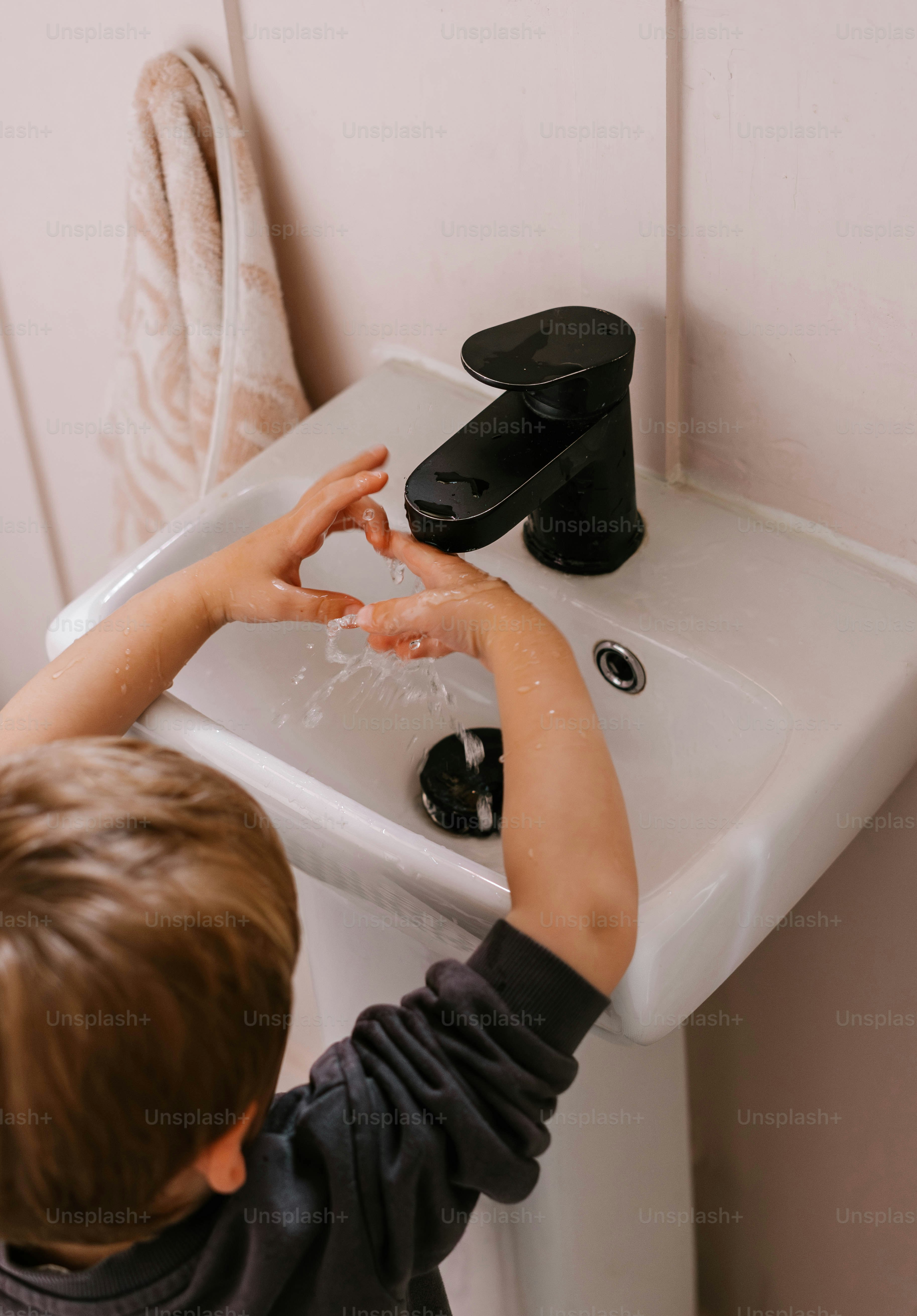 A young boy washing his hands in a sink