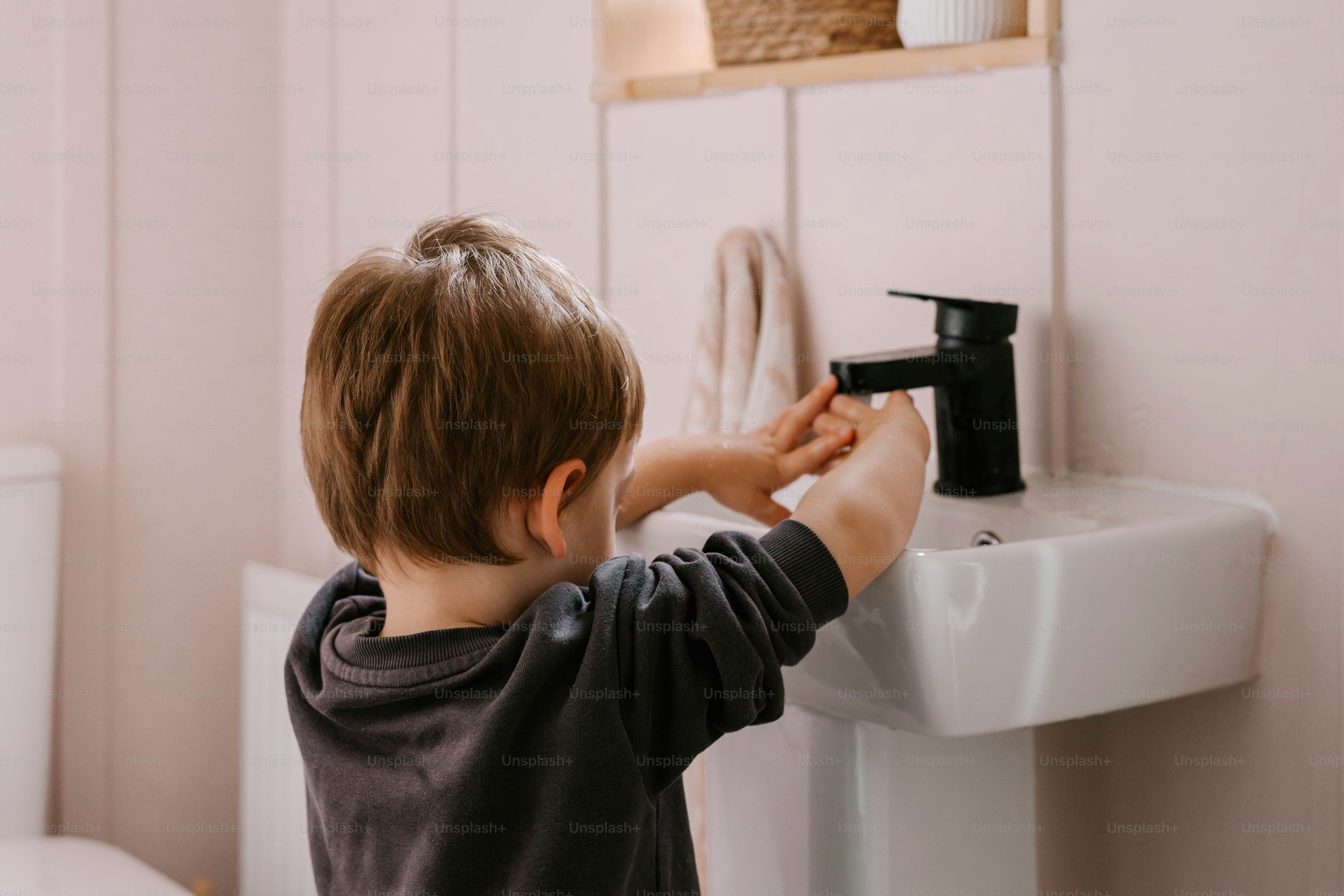 Ein kleiner Junge, der vor einem Waschbecken steht