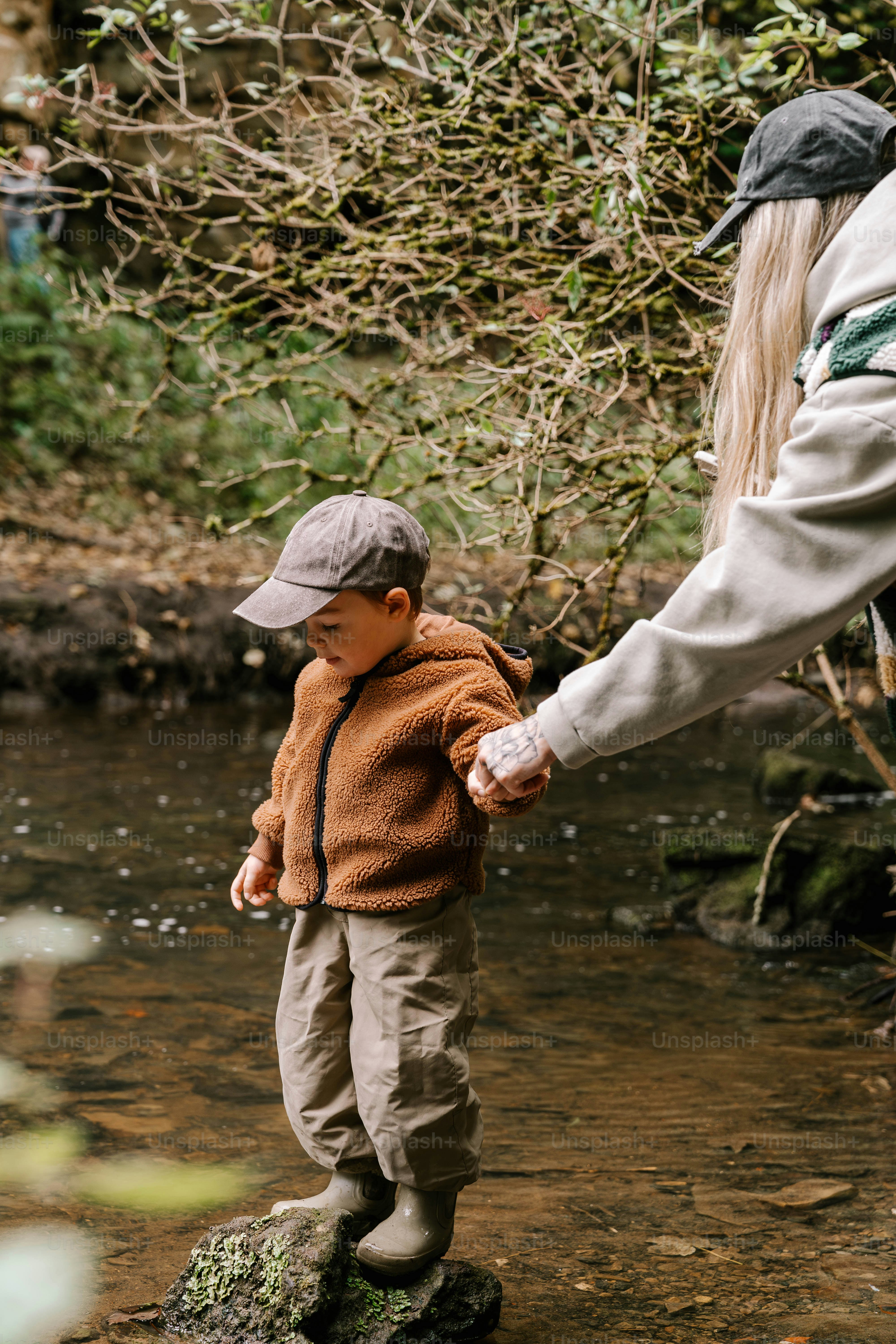A woman holding a child's hand while standing on a rock
