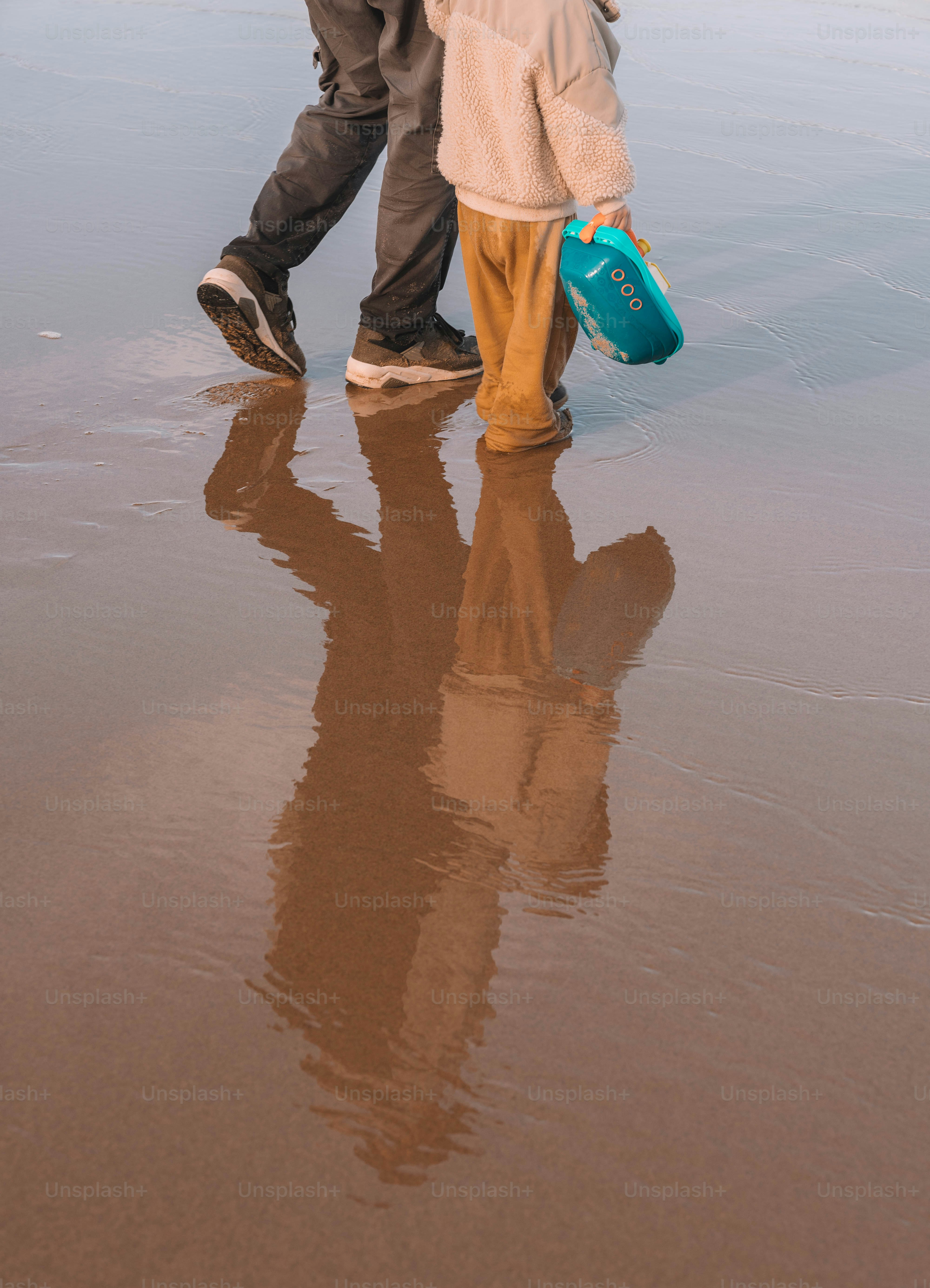Seorang pria dan seorang anak berjalan di pantai