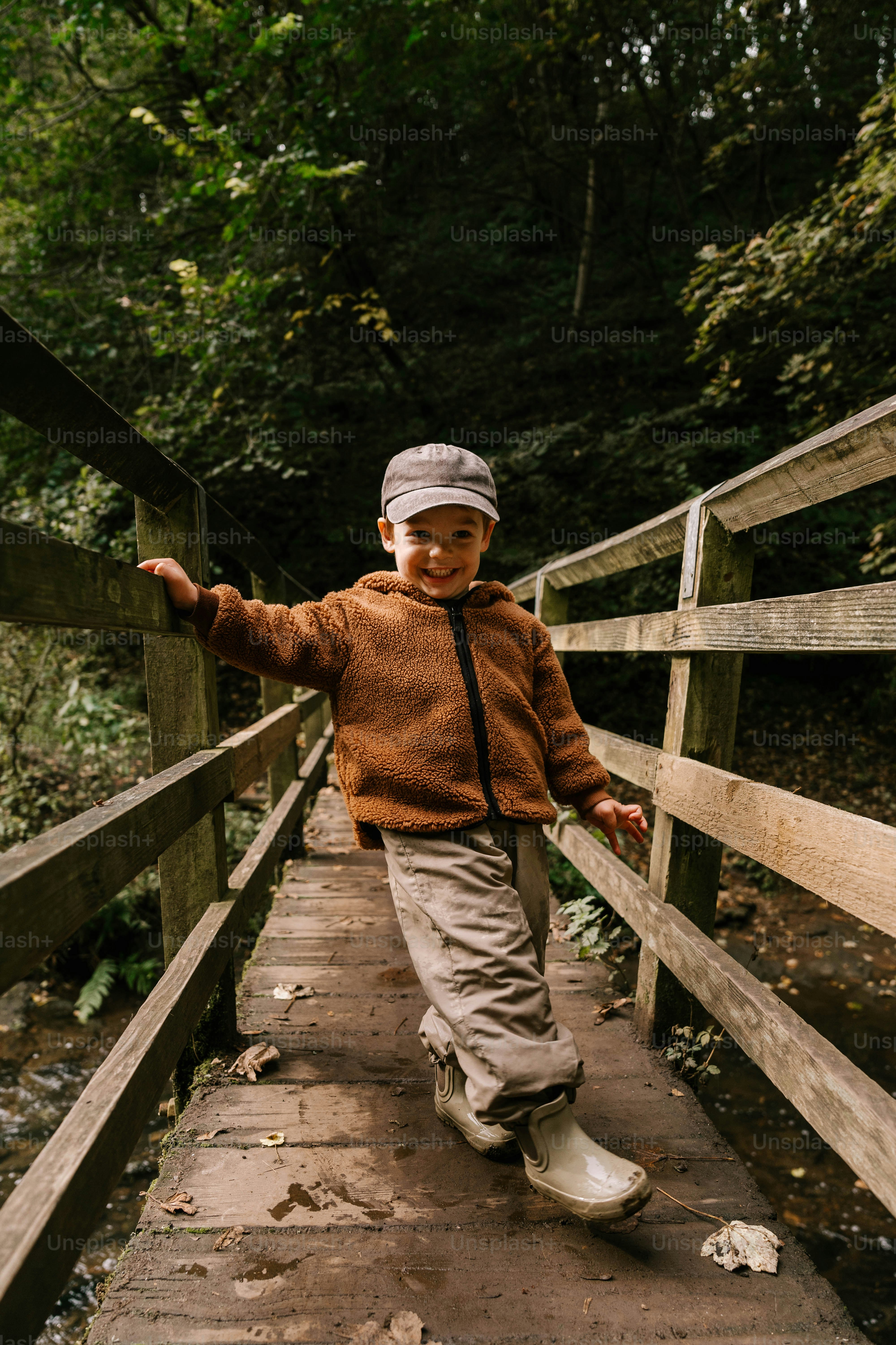 A young boy walking across a wooden bridge