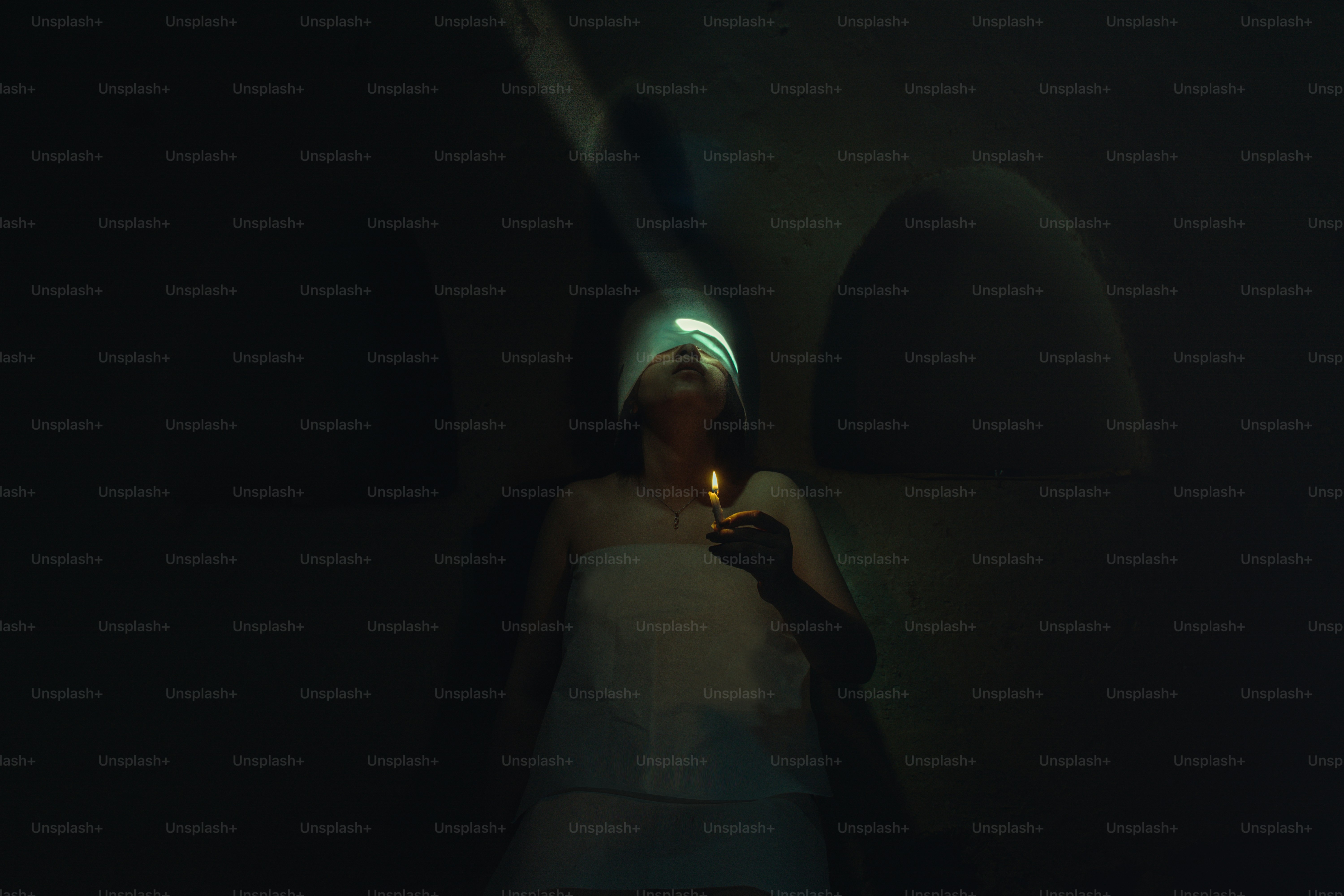 Eine Frau, die in einem dunklen Raum steht und eine brennende Kerze in der Hand hält