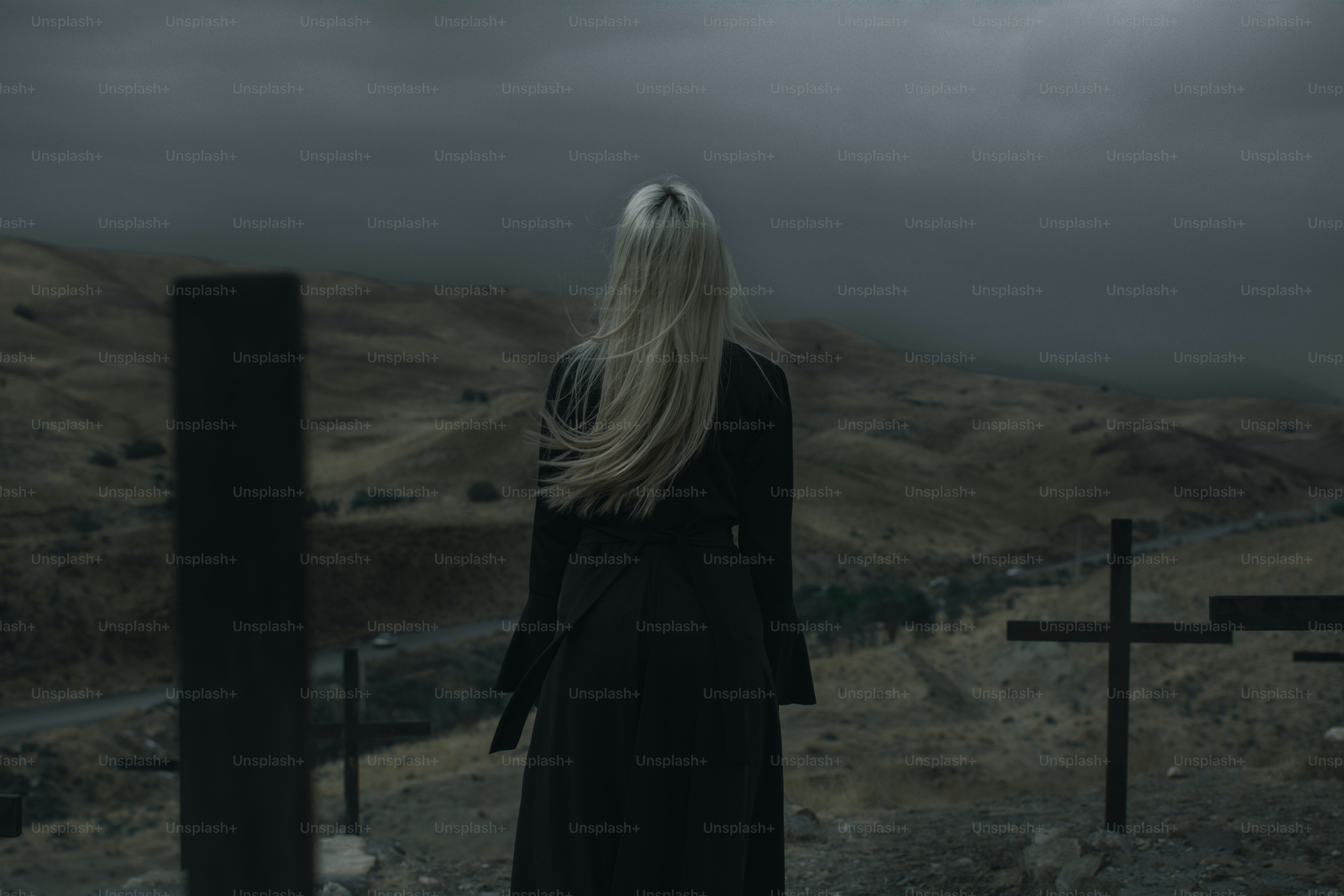 A woman in a long black dress standing in front of a cross