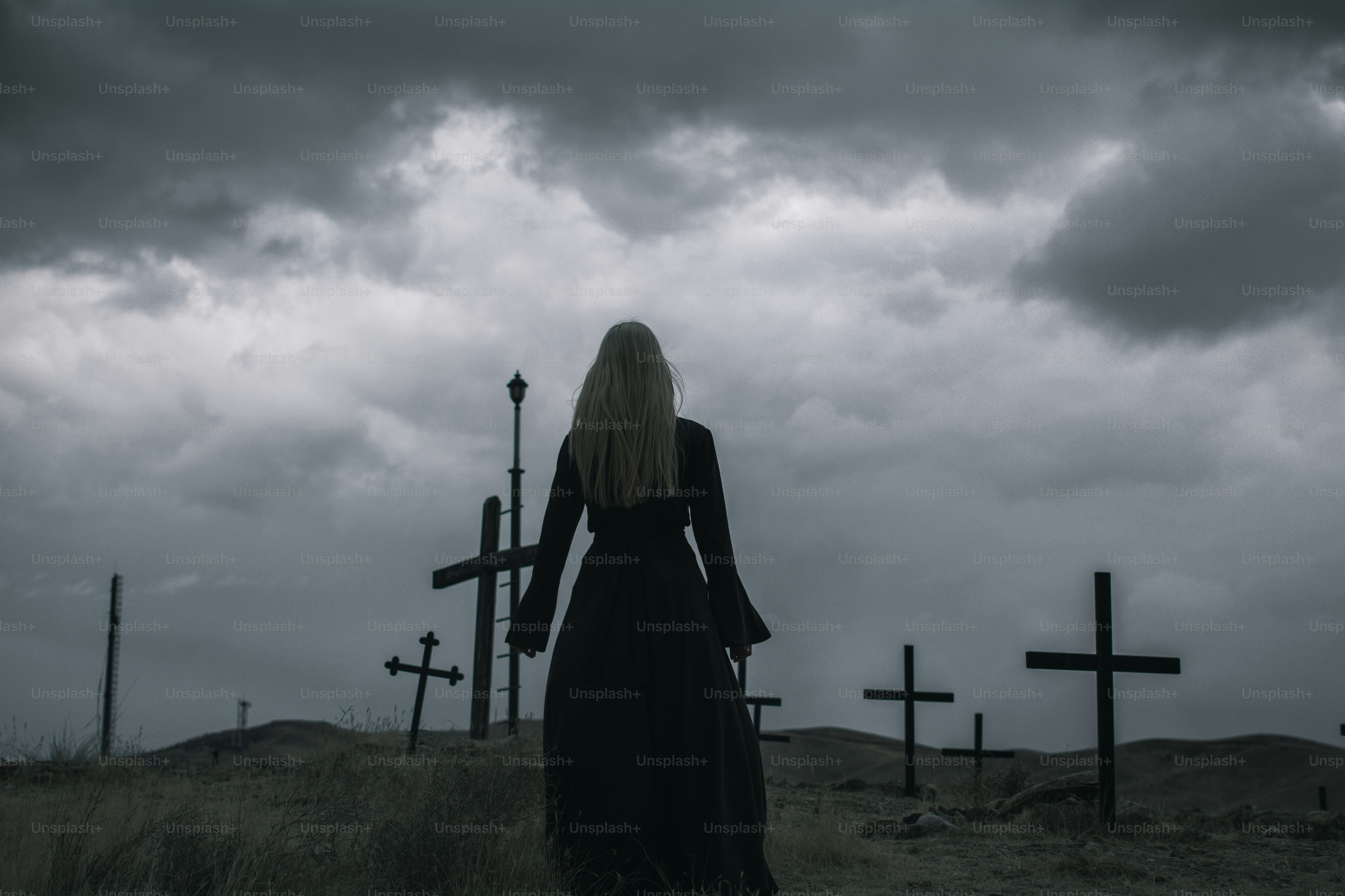 Una mujer con un vestido largo de pie frente a cruces