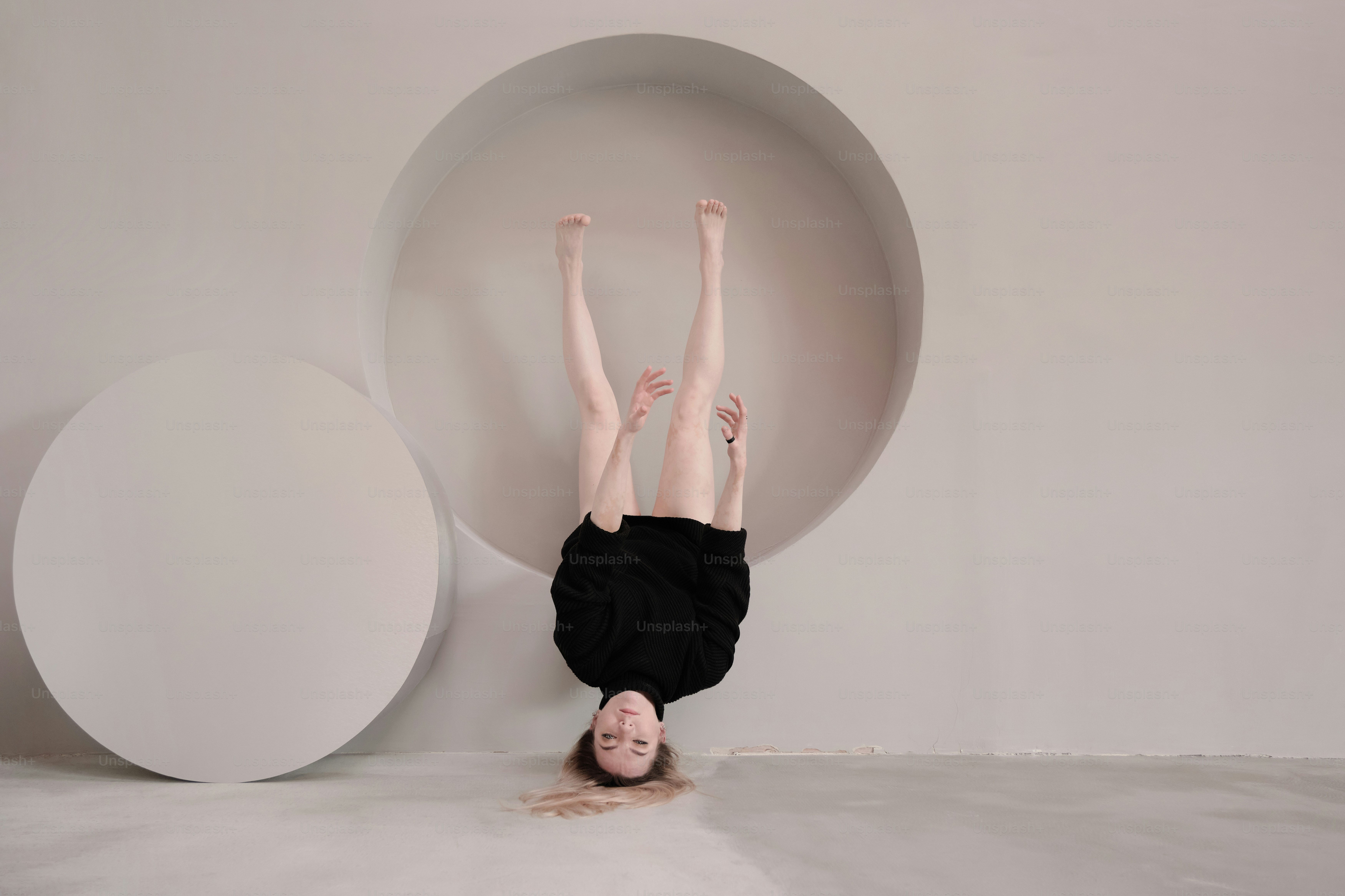A person upside down in front of a white wall