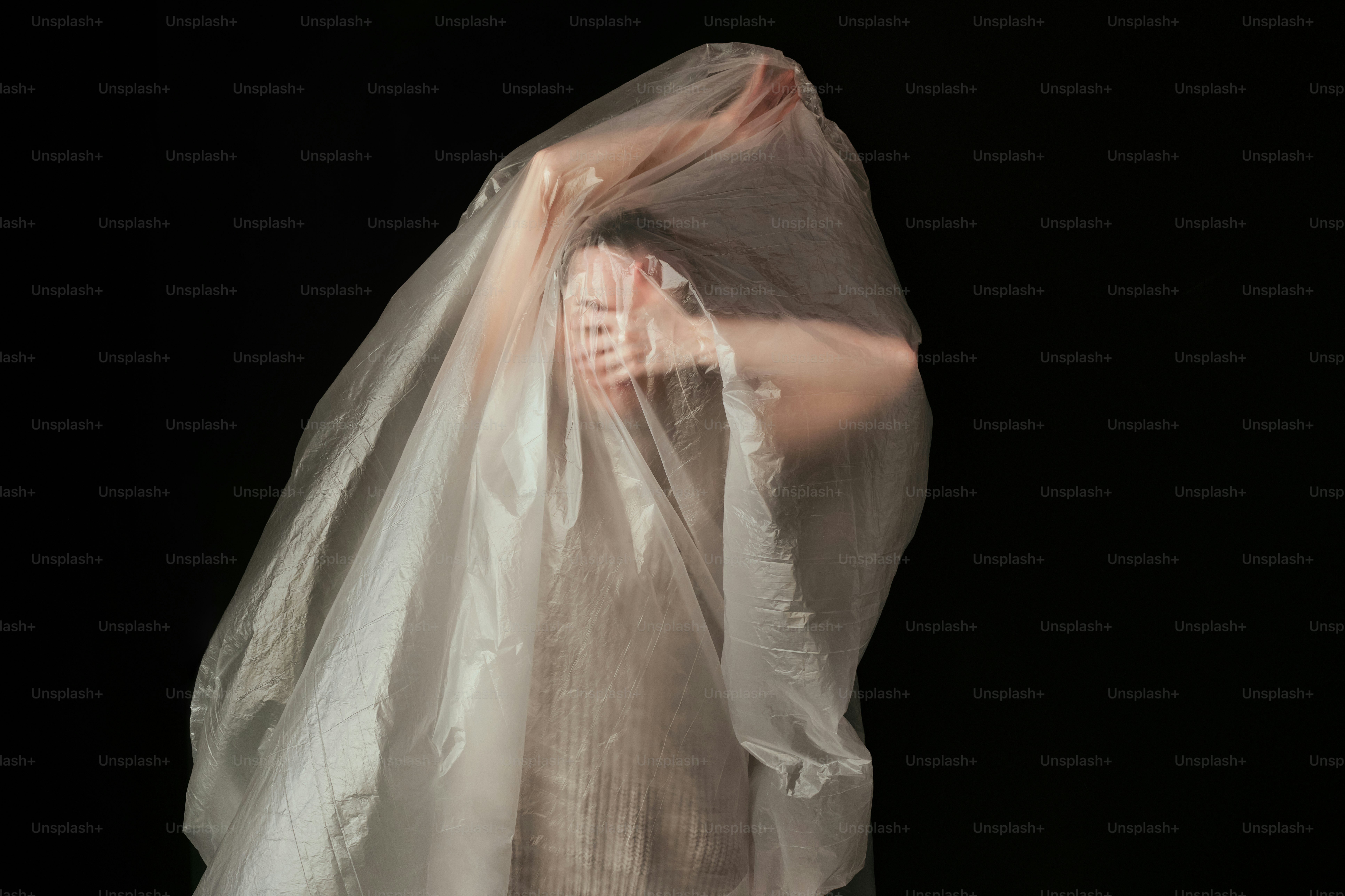 A woman wrapped in a plastic bag on a black background