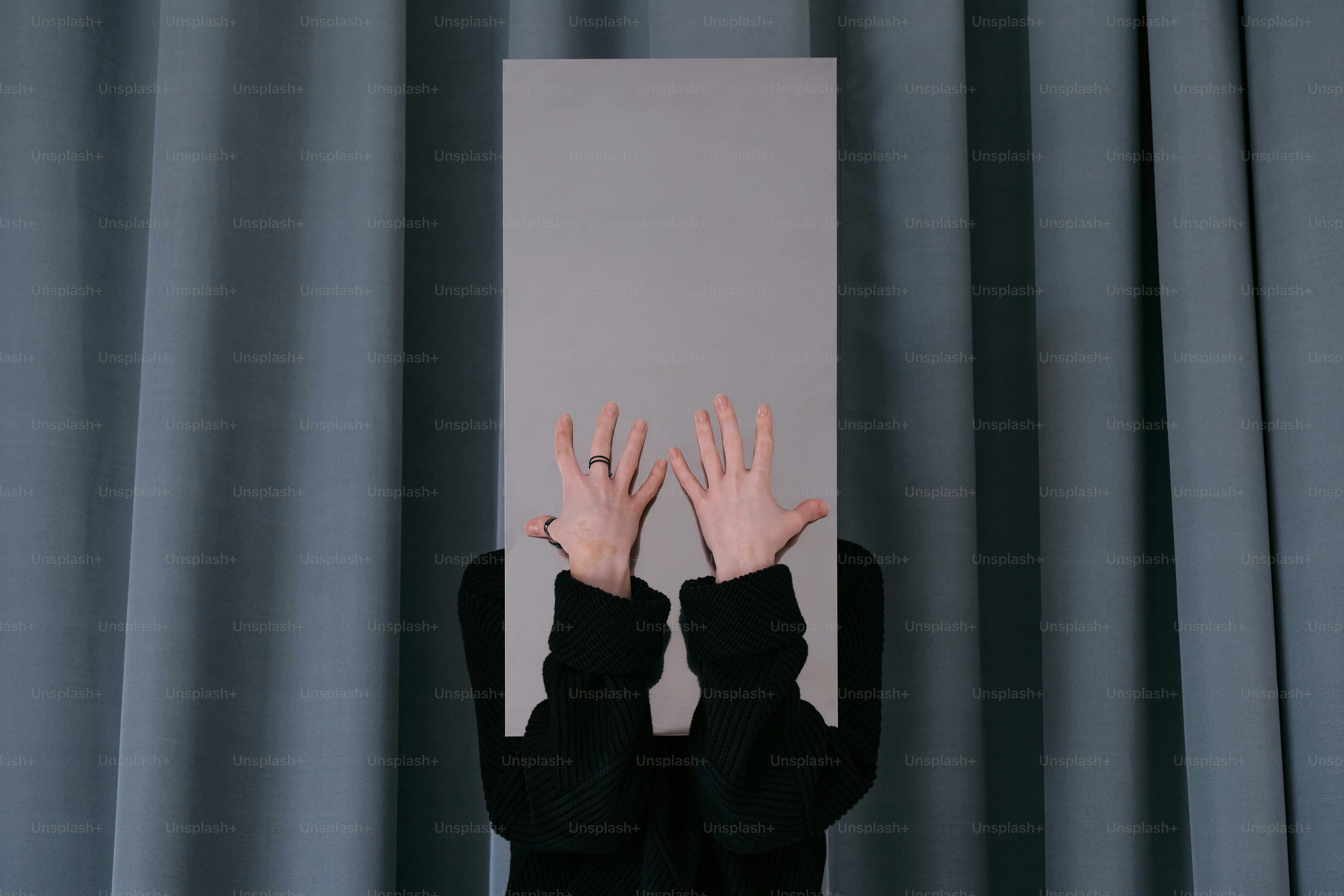 A person with their hands up behind a sign