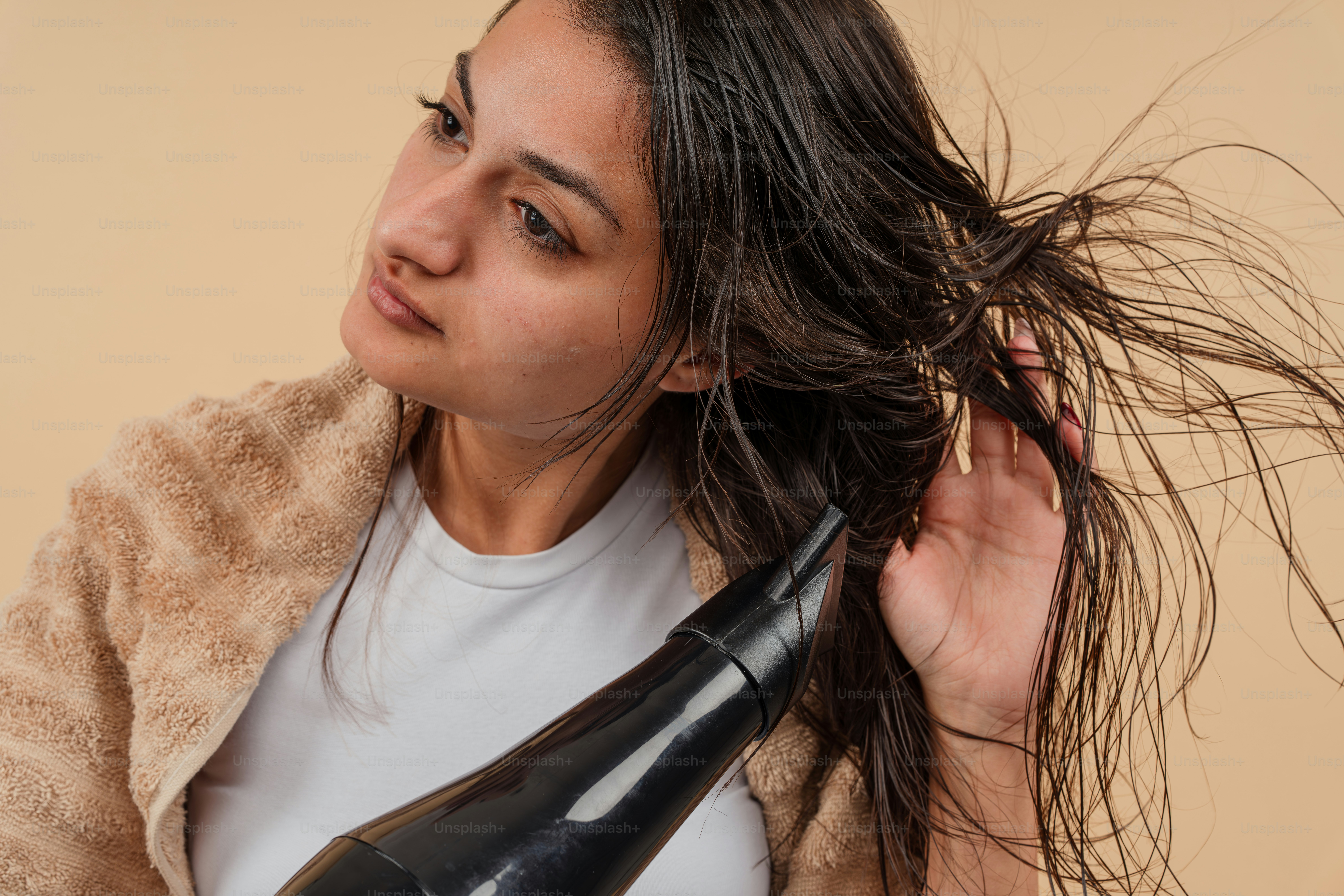 Eine Frau, die sich die Haare mit einem Fön föhnt