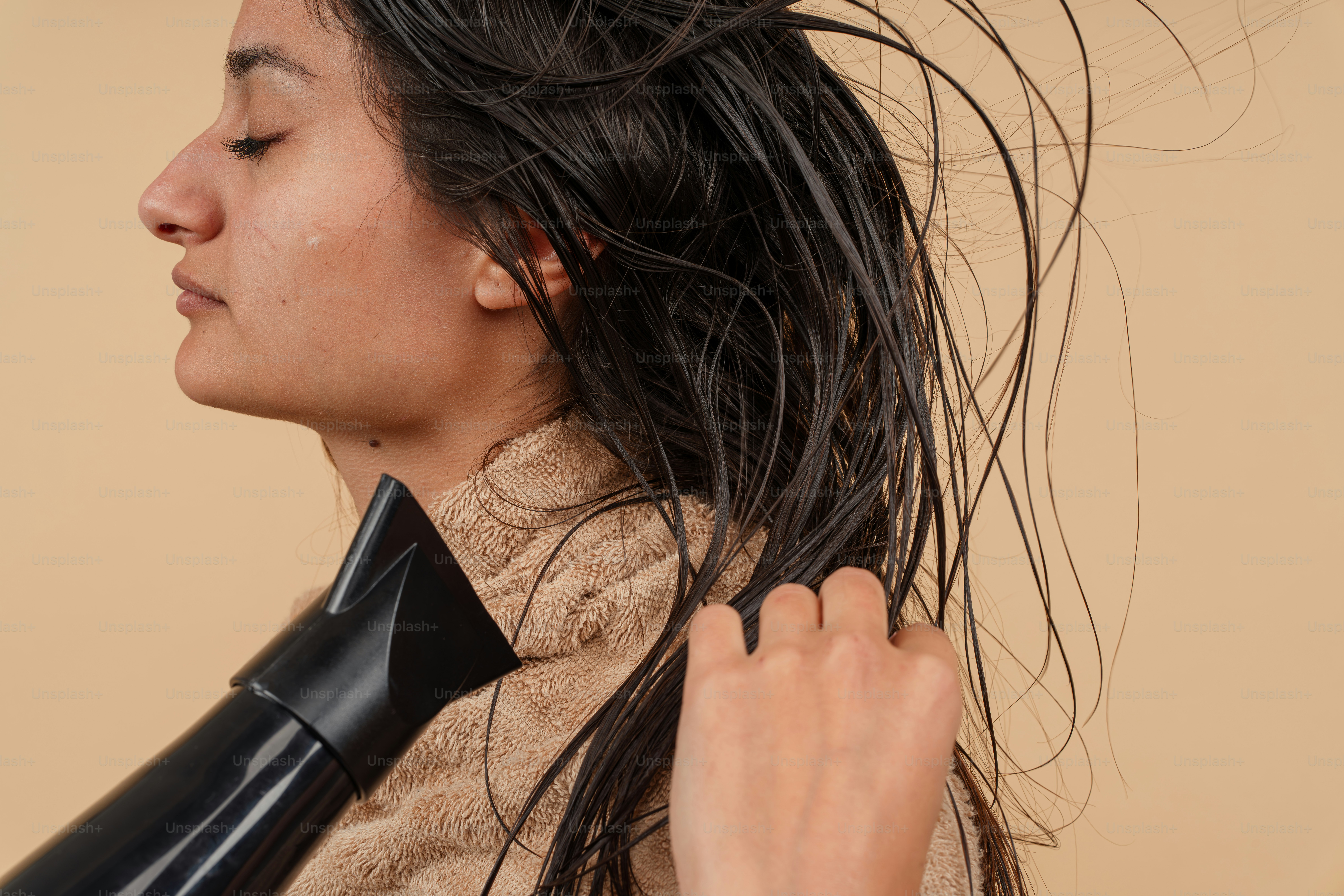 Eine Frau, die sich die Haare mit einem Fön föhnt