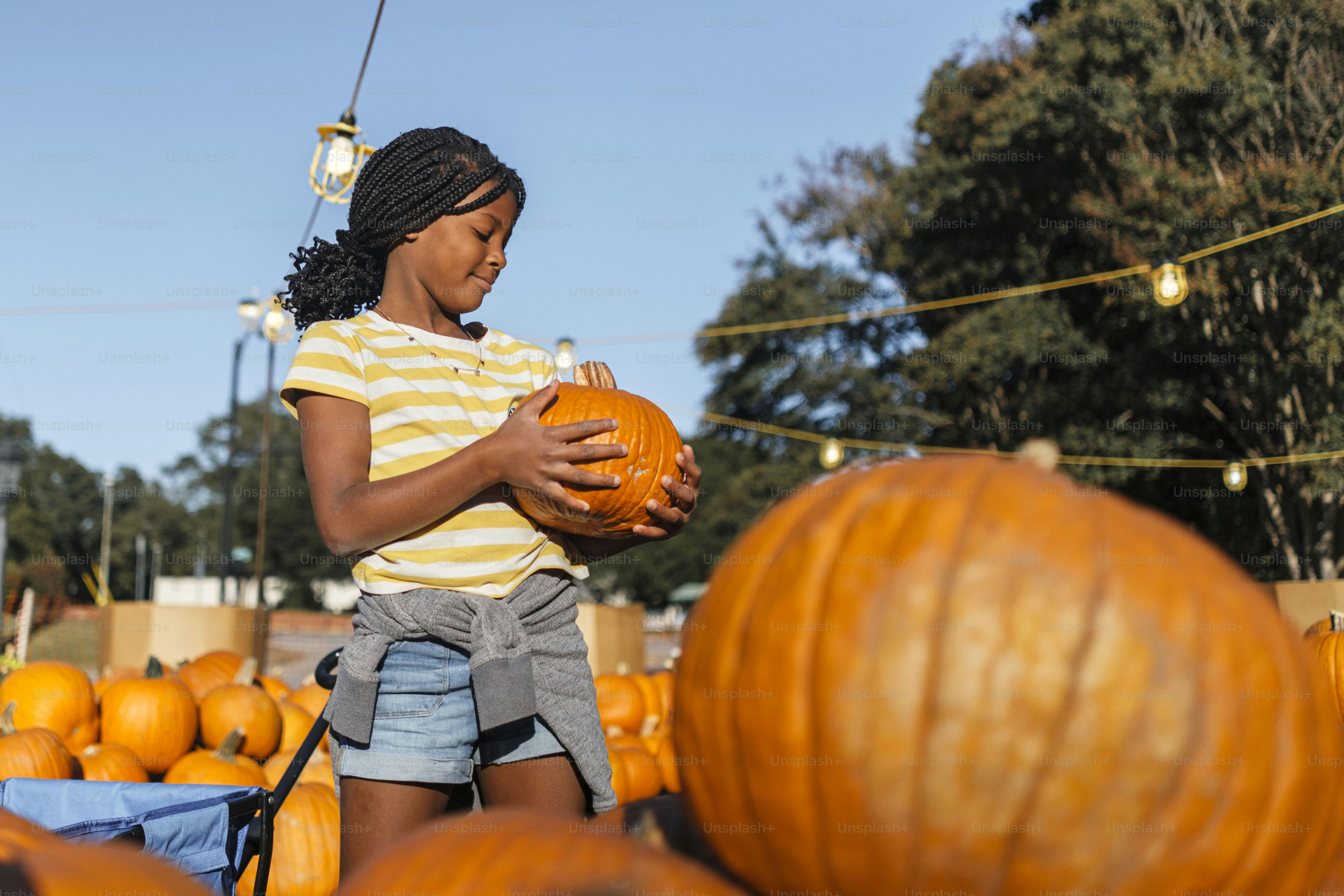 A little girl standing next to a pile of pumpkins photo – Girl Image on ...