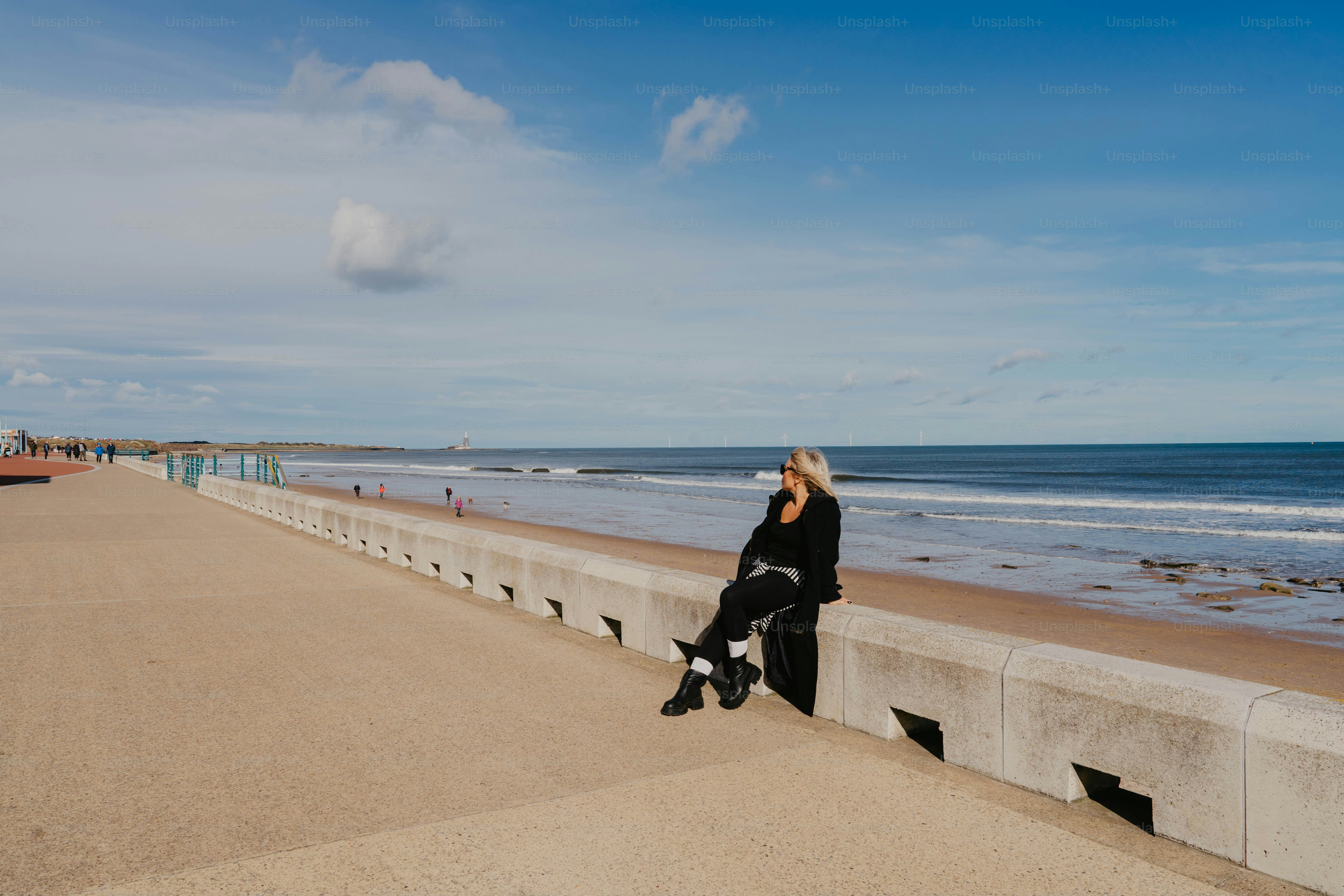 A person sitting on a concrete ledge near the ocean