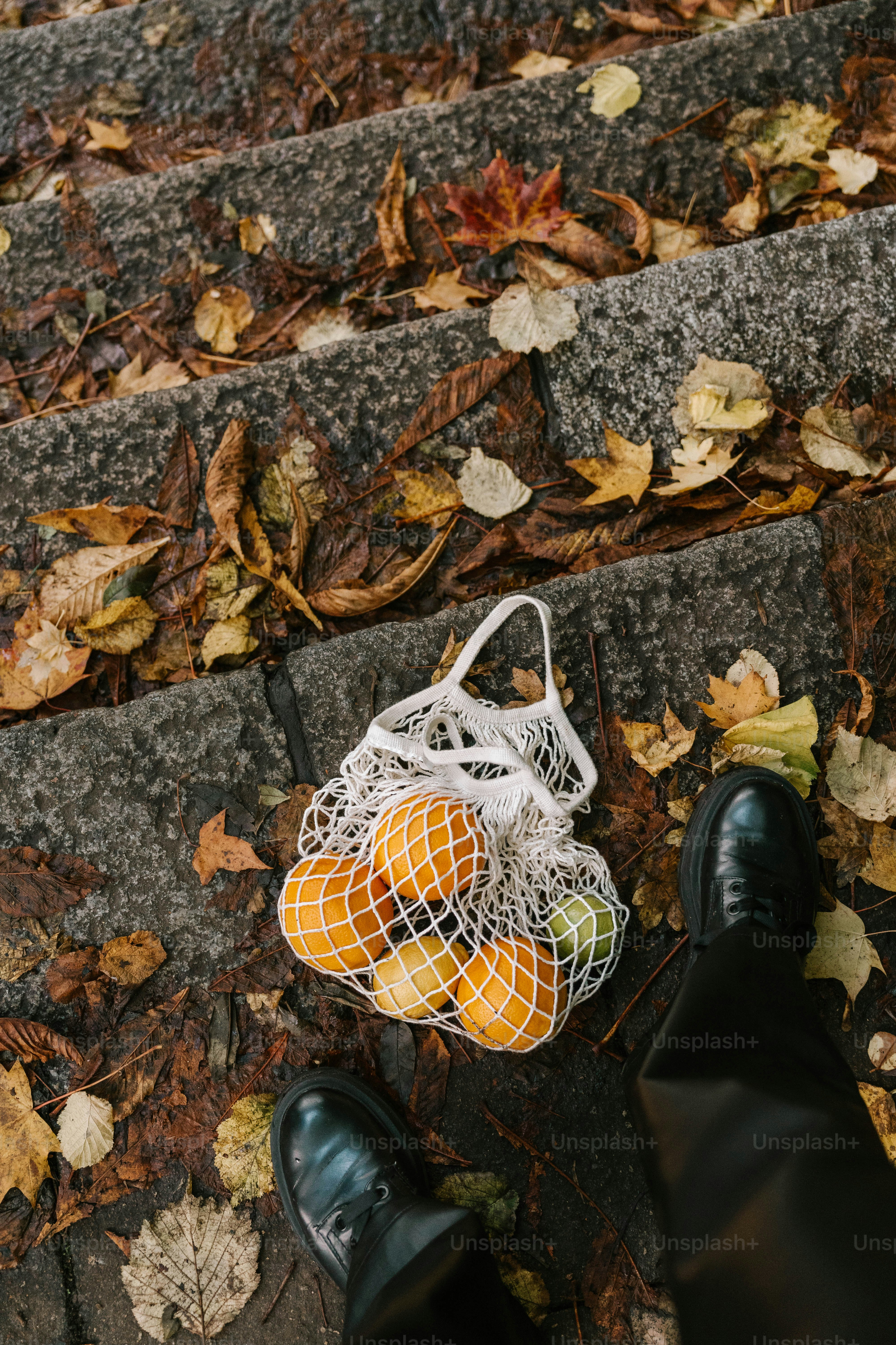 A person standing next to a bag of oranges