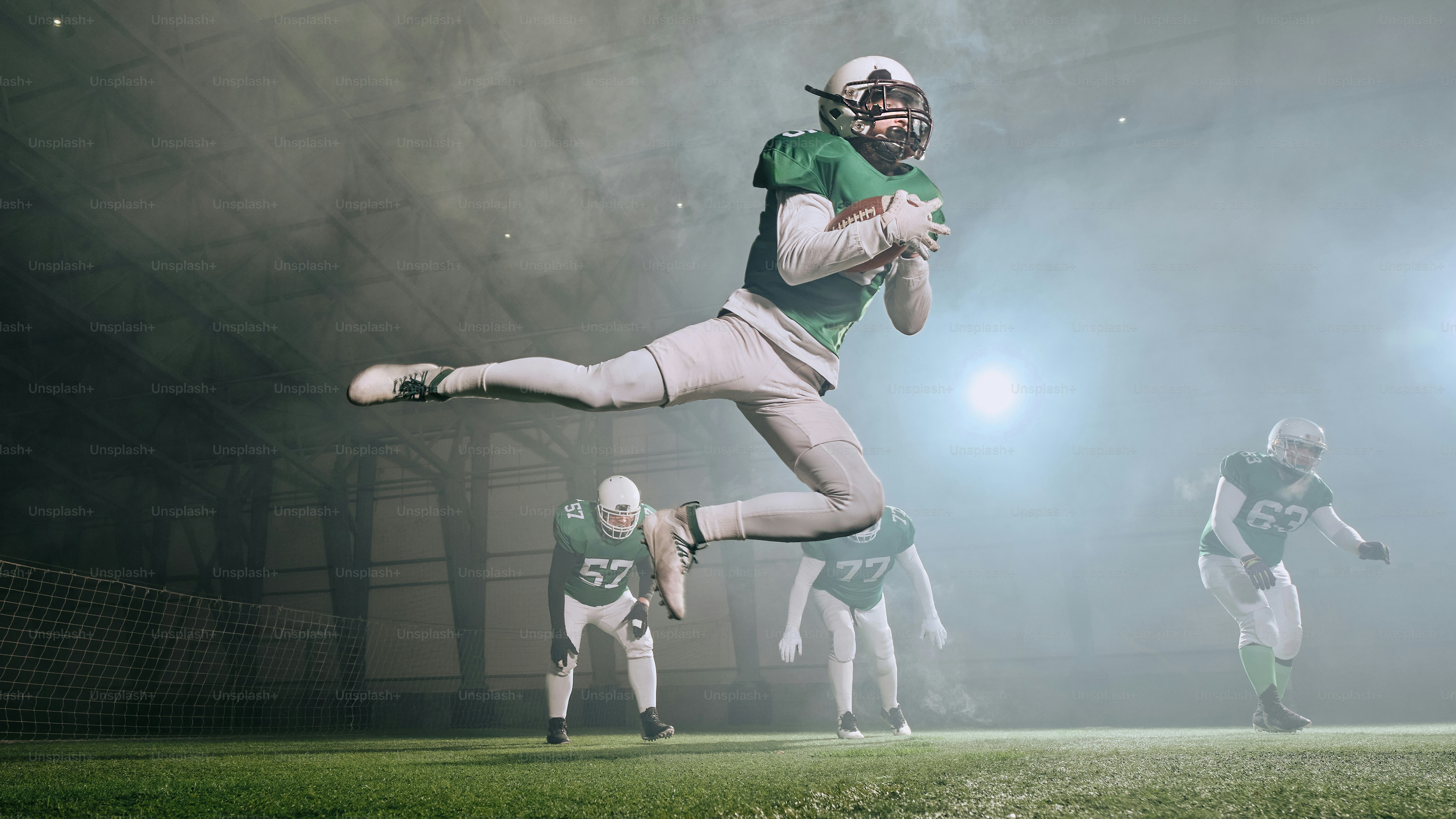 A football player is jumping in the air to catch a ball