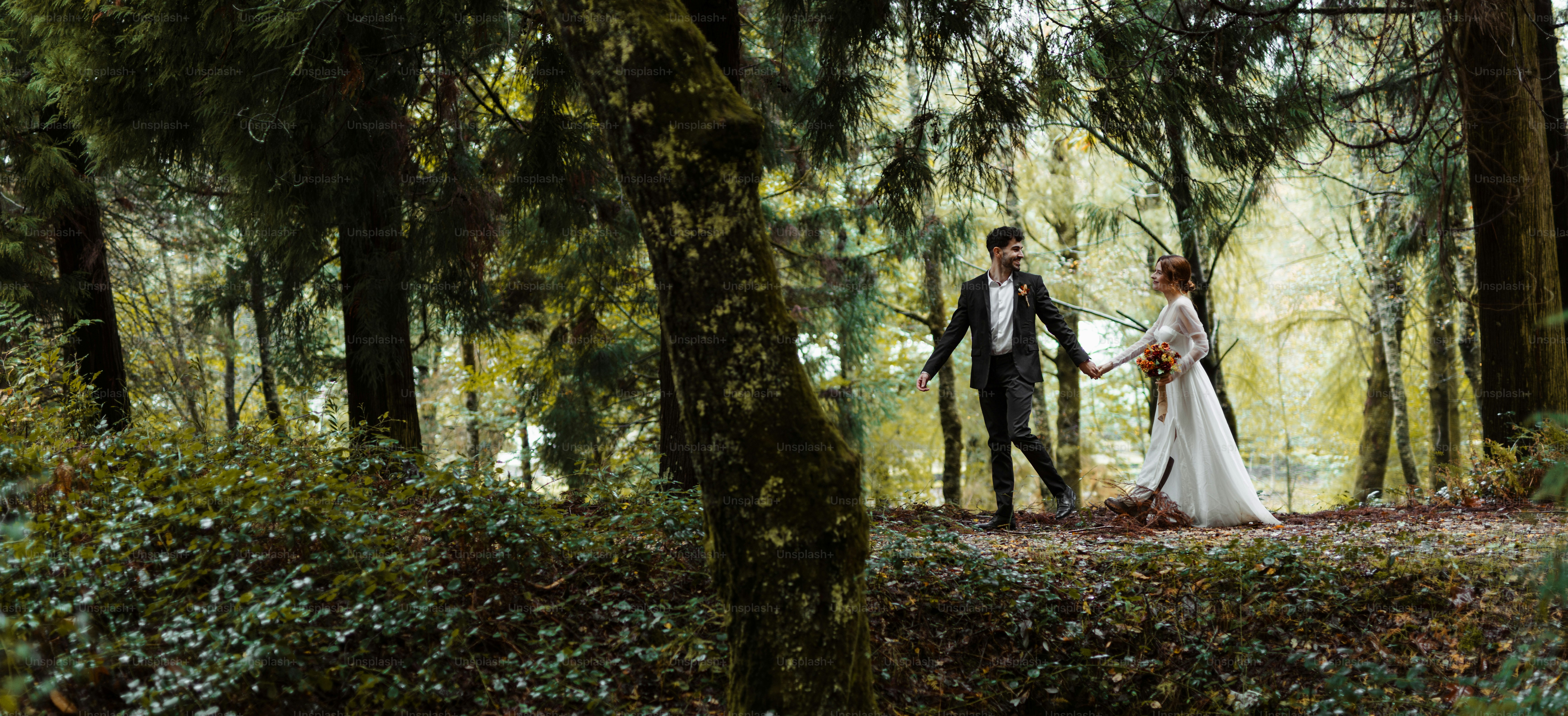 A bride and groom walking through the woods
