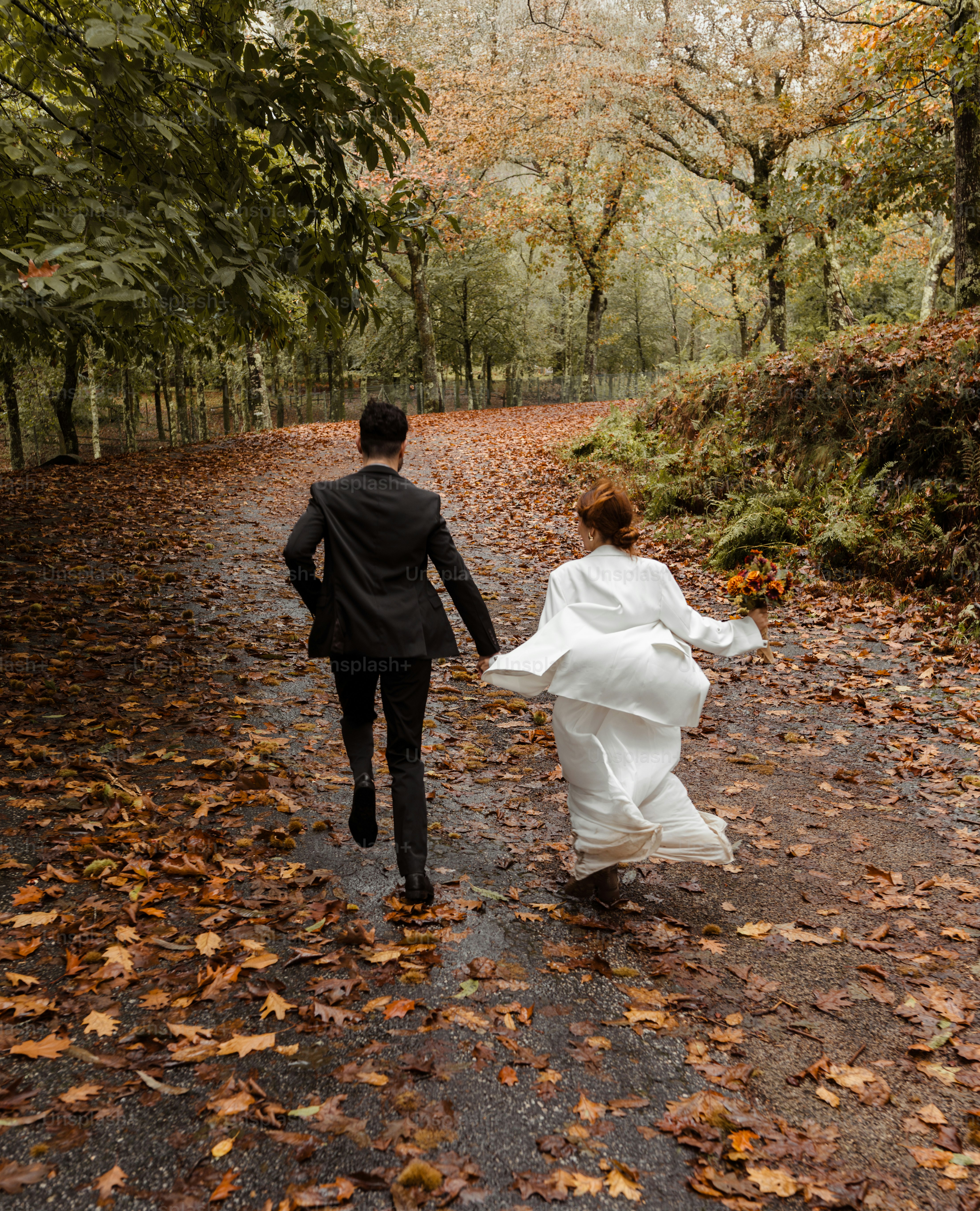 A bride and groom walking down a path in the woods