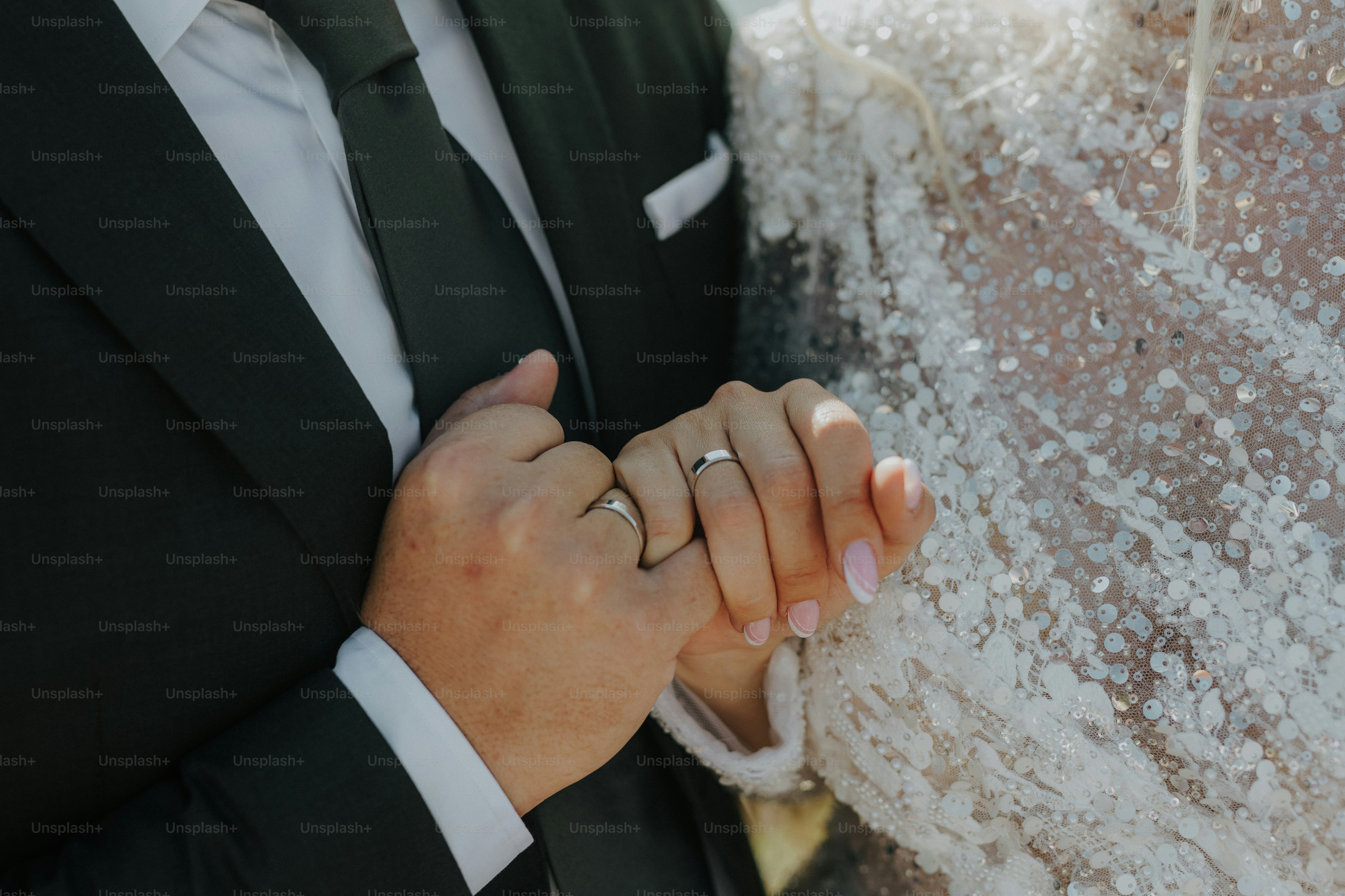 A bride and groom holding hands in front of a wall